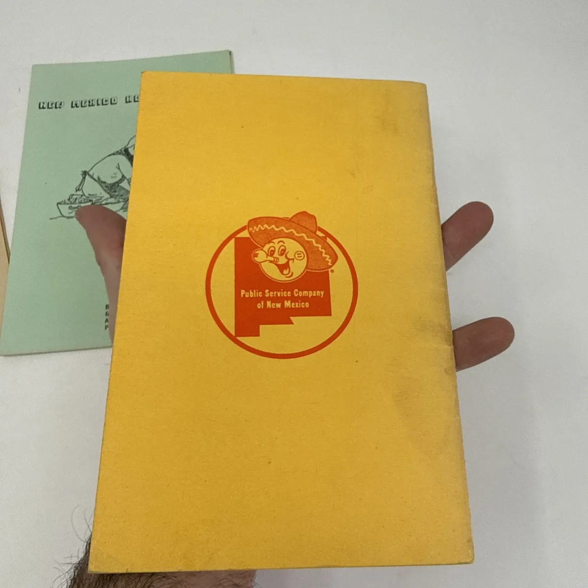 A yellow Public Service Company of New Mexico cookbook with the sombrero-character utility-company logo