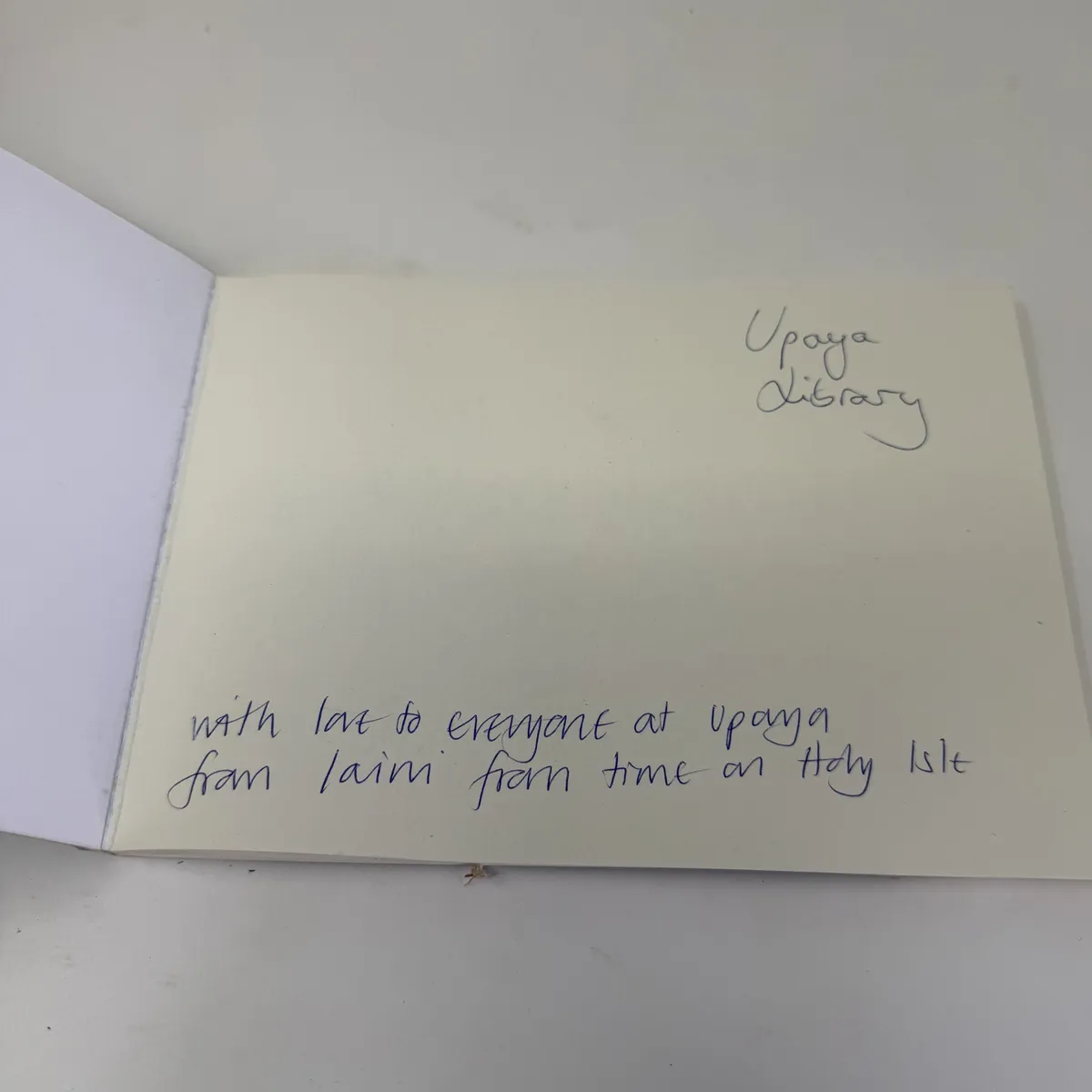 The front free endpaper with handwritten inscription Upaya Library and With love to everyone at Upaya from Laini from time on Holy Isle in blue ballpoint