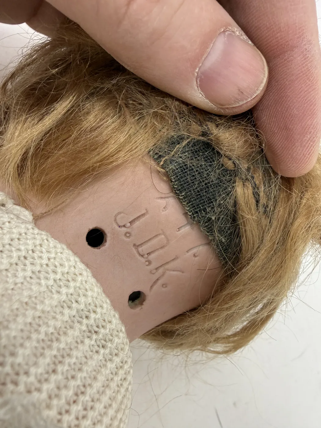 A second very close detail of the back-of-head mark, framed even tighter on the J. D. K. line at the bottom. The capitals are nearly Roman in proportion with small flat-stop periods between each letter and a clear narrow space before the next letter. The pinkish-tan bisque surface shows a small amount of factory tooling around the lower edge of the marking.