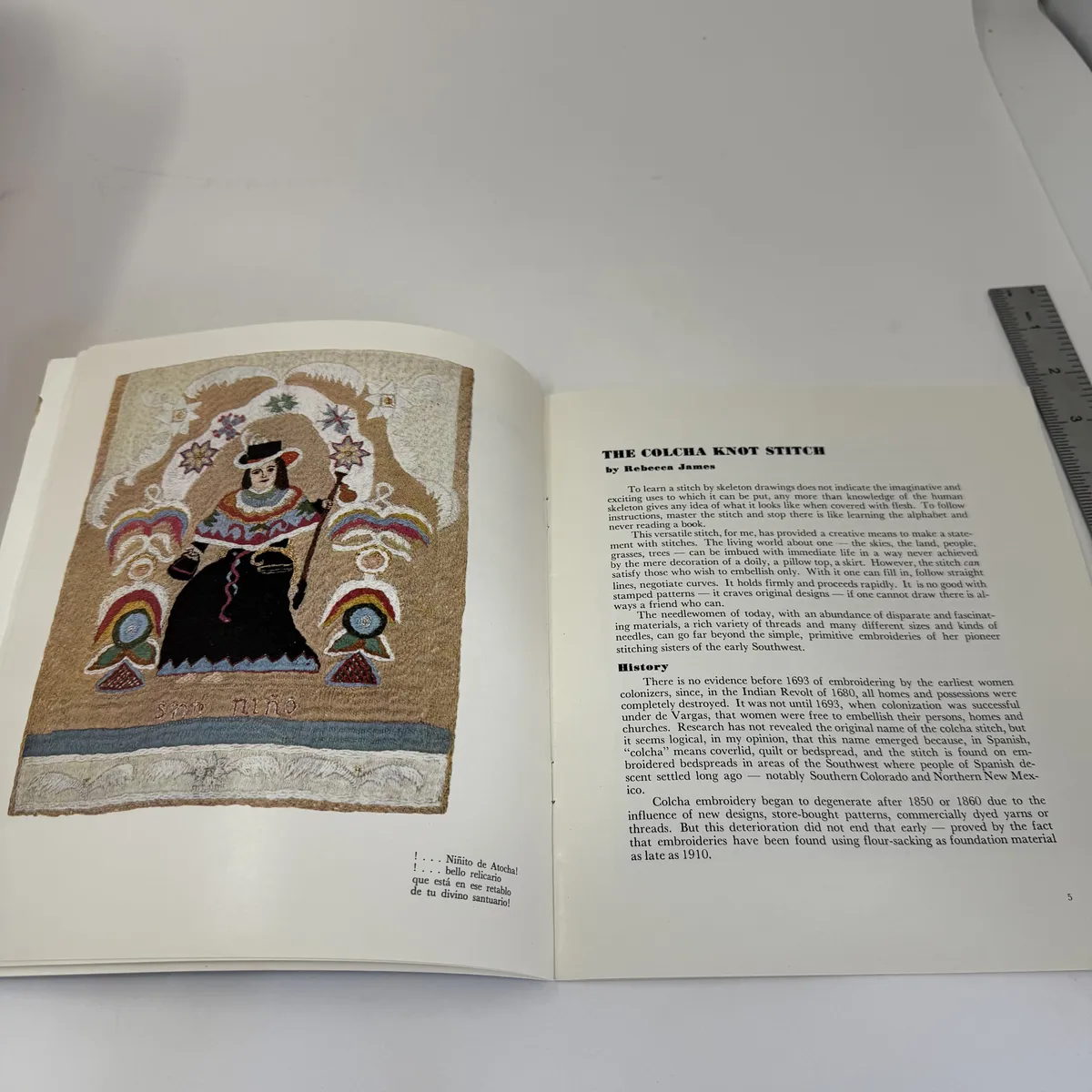 A two-page spread with one of Rebecca James's embroidered pictures on the left page and the opening of her essay The Colcha Knot Stitch by Rebecca James on the right page, discussing the history of NM colcha embroidery beginning before 1685