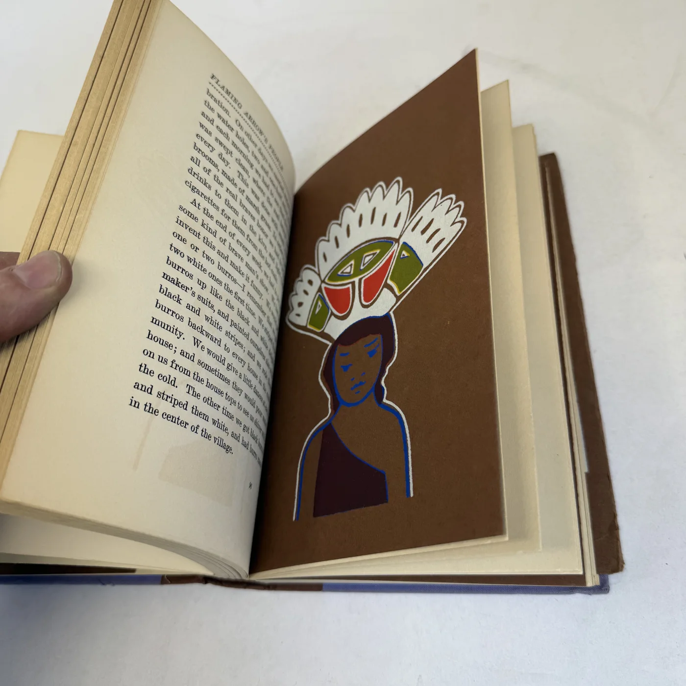 A second Paytiamo color drawing: a figure in a great feathered headdress with green and red banding, shown in profile on the brown plate ground.