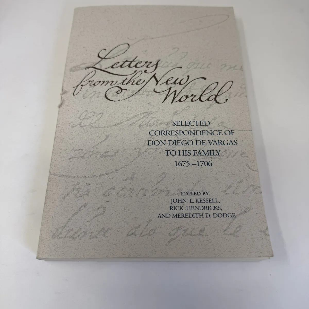 The front cover of Letters from the New World by Diego de Vargas, with elegant calligraphic title typography over a faint reproduction of period Spanish manuscript script and the editor names John L. Kessell, Rick Hendricks, and Meredith D. Dodge.