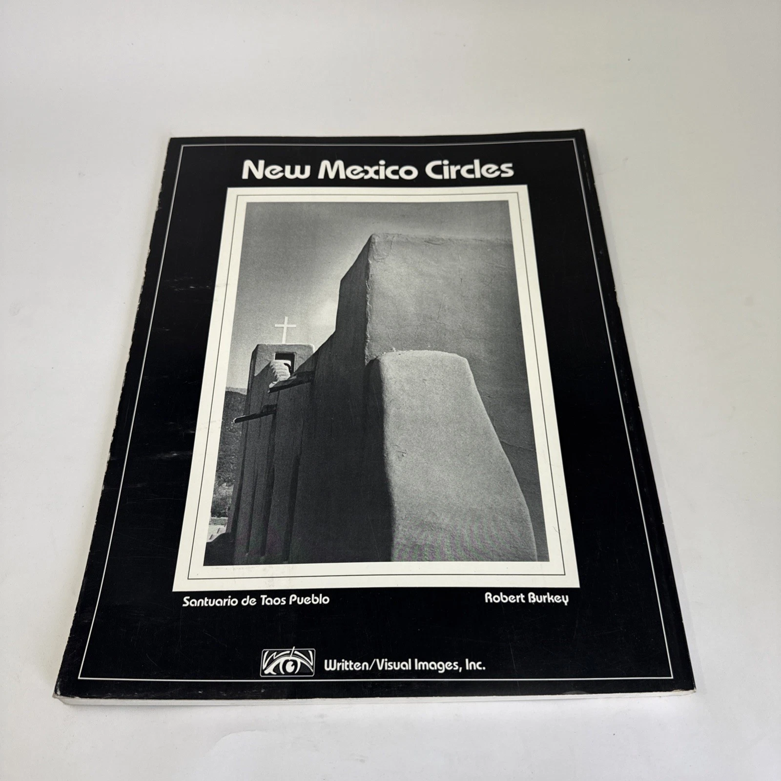 Back cover of New Mexico Circles showing a B&W photograph of the Santuario de Taos Pueblo with adobe wall and cross