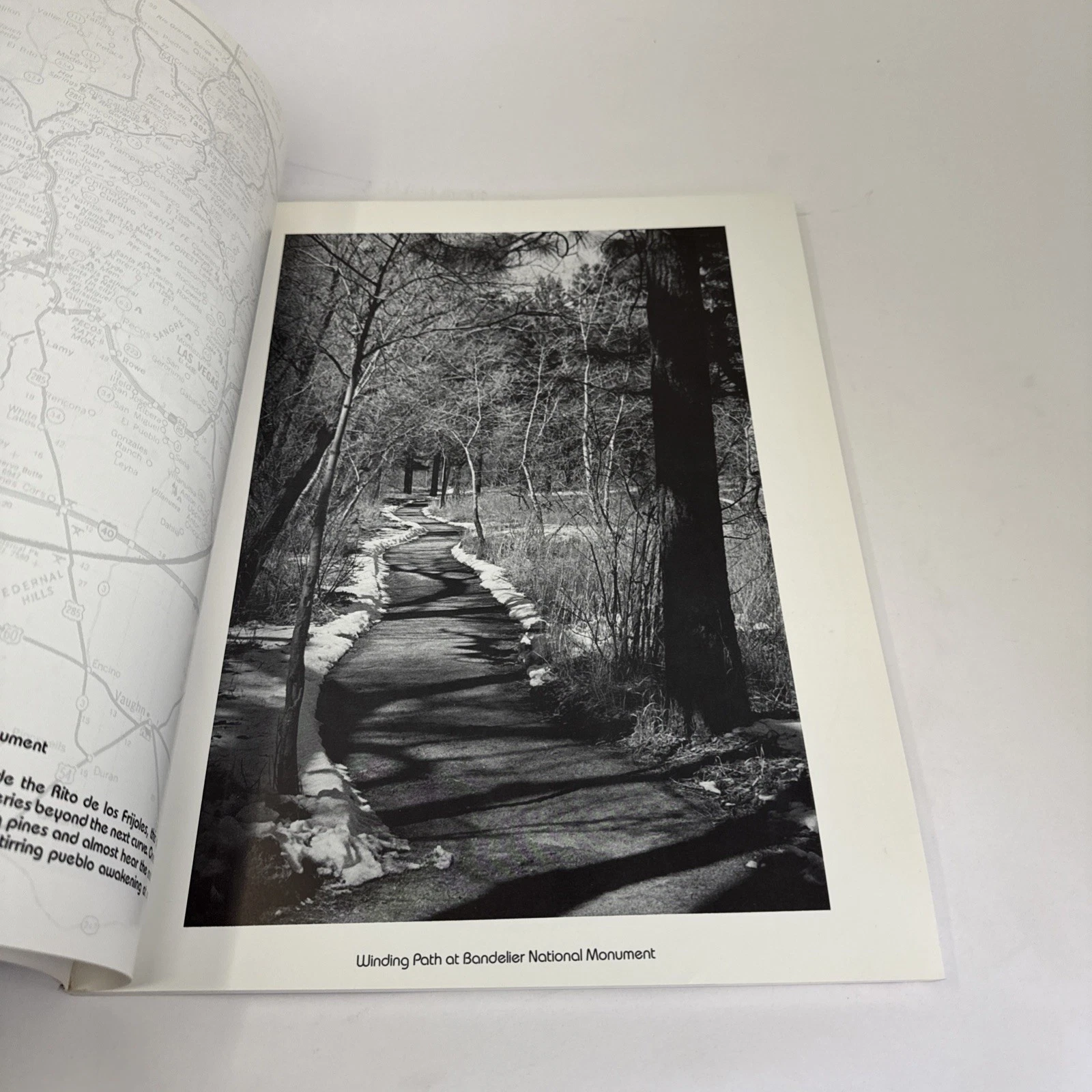 An interior spread showing a B&W photo of a winding path at Bandelier National Monument with caption text and a small regional map