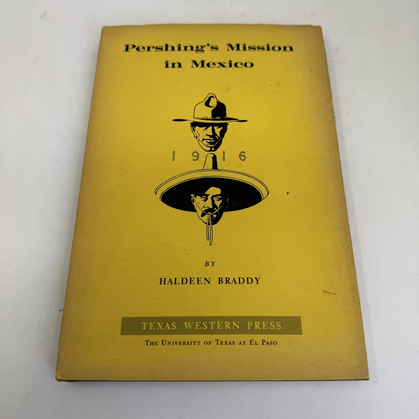 Yellow dust jacket of Pershing's Mission in Mexico by Haldeen Braddy showing dual silhouette portraits of John J. Pershing in cavalry hat and Pancho Villa in sombrero with 1916 between them, Texas Western Press El Paso UTEP, Carl Hertzog designed
