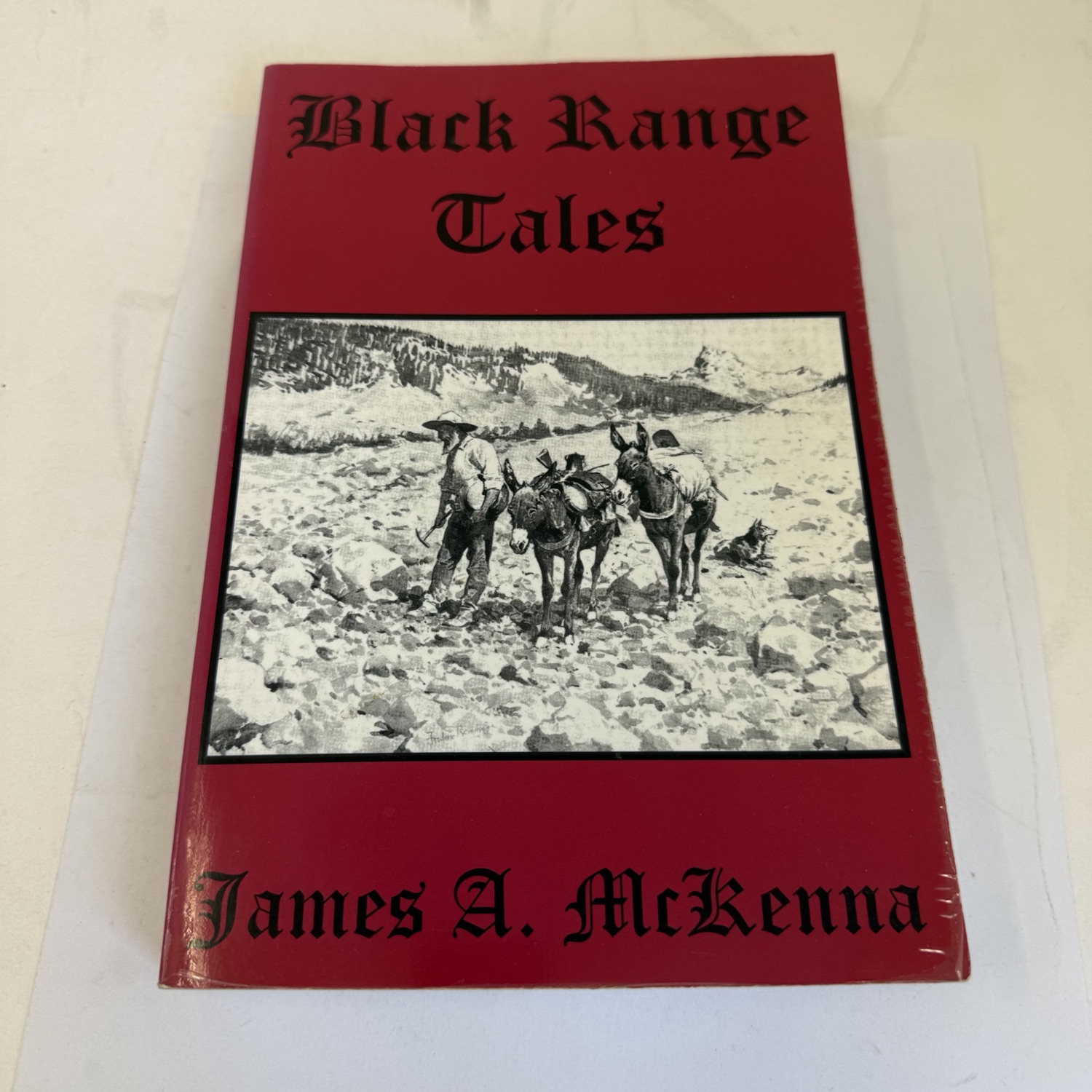 Front cover of Black Range Tales by James A. McKenna — red cover with black-and-white photograph of a prospector leading a pack mule through mountain terrain, Old English lettering, author name at bottom, High-Lonesome Books 2002 reprint of the 1936 Wilson-Erickson first edition