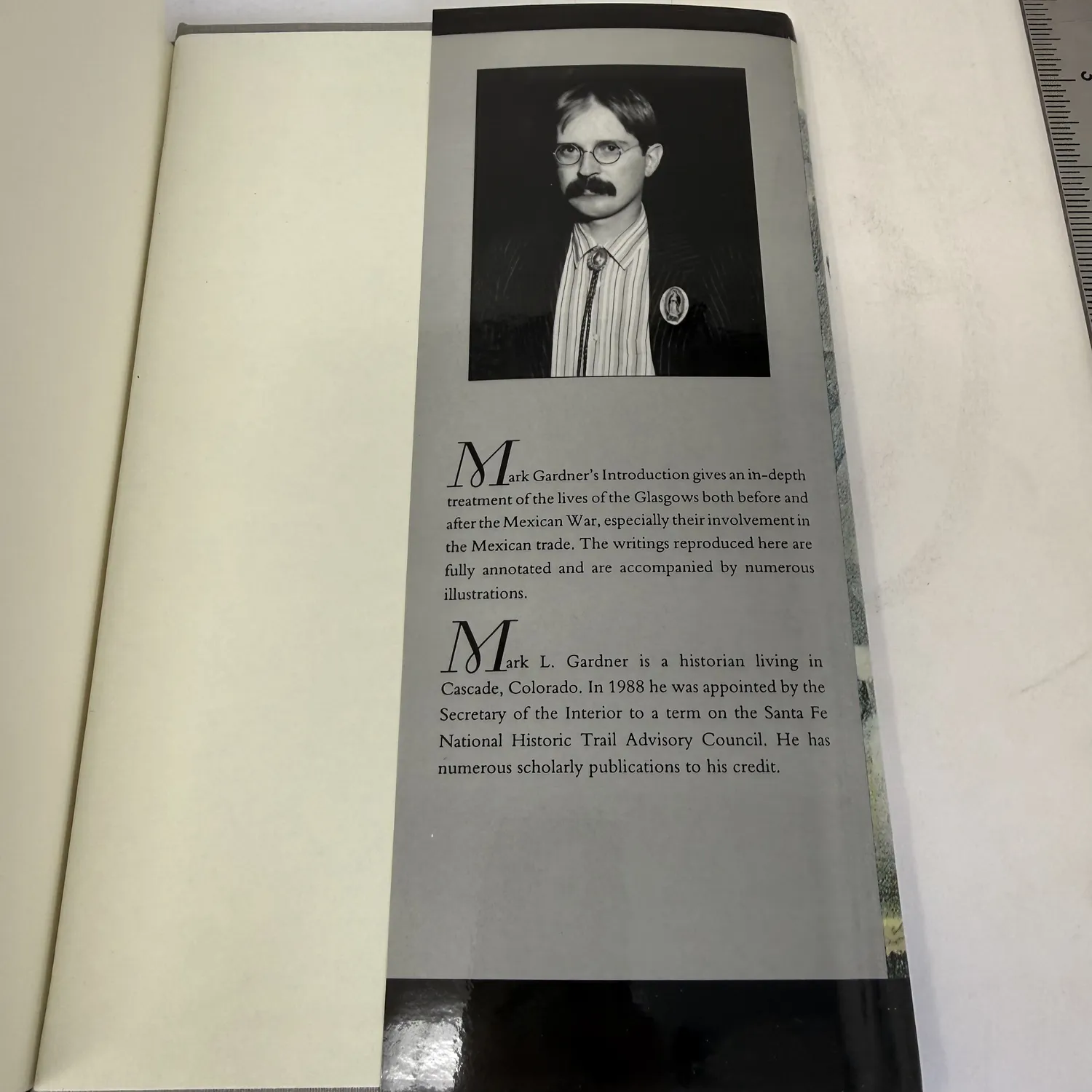 Rear dust jacket flap of Brothers on the Santa Fe and Chihuahua Trails showing black and white portrait photograph of editor Mark L. Gardner wearing glasses and bolo tie, with biographical text identifying him as a historian living in Cascade Colorado appointed by the Secretary of the Interior to the Santa Fe National Historic Trail Advisory Council in 1988, photographed at New Mexico Literacy Project