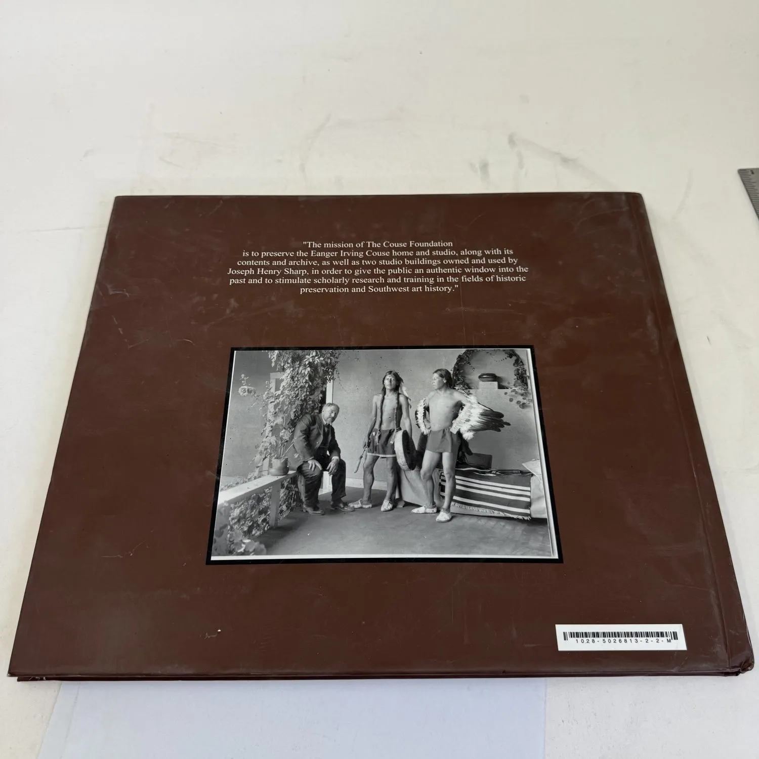 Back cover of Couse-Sharp Historic Site Historic Building Assessment showing Couse Foundation mission statement referencing Eanger Irving Couse and Joseph Henry Sharp, with historic black and white photograph of E.I. Couse painting in his Taos studio with Native American models — primary source document from the Taos Society of Artists era photographed by Josh Eldred at NMLP workspace