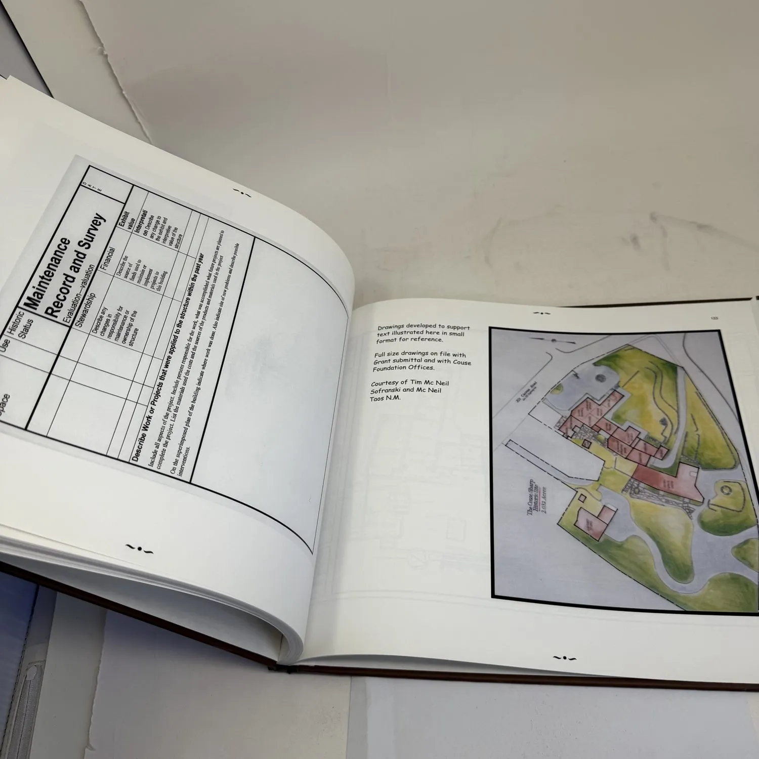 Interior spread from Couse-Sharp Historic Building Assessment showing Maintenance Record and Survey form template alongside full-color site plan drawing of building layout by Tim McNeil, Sofranski and McNeil, Taos NM — documentary architectural field documentation photographed by Josh Eldred at NMLP workspace
