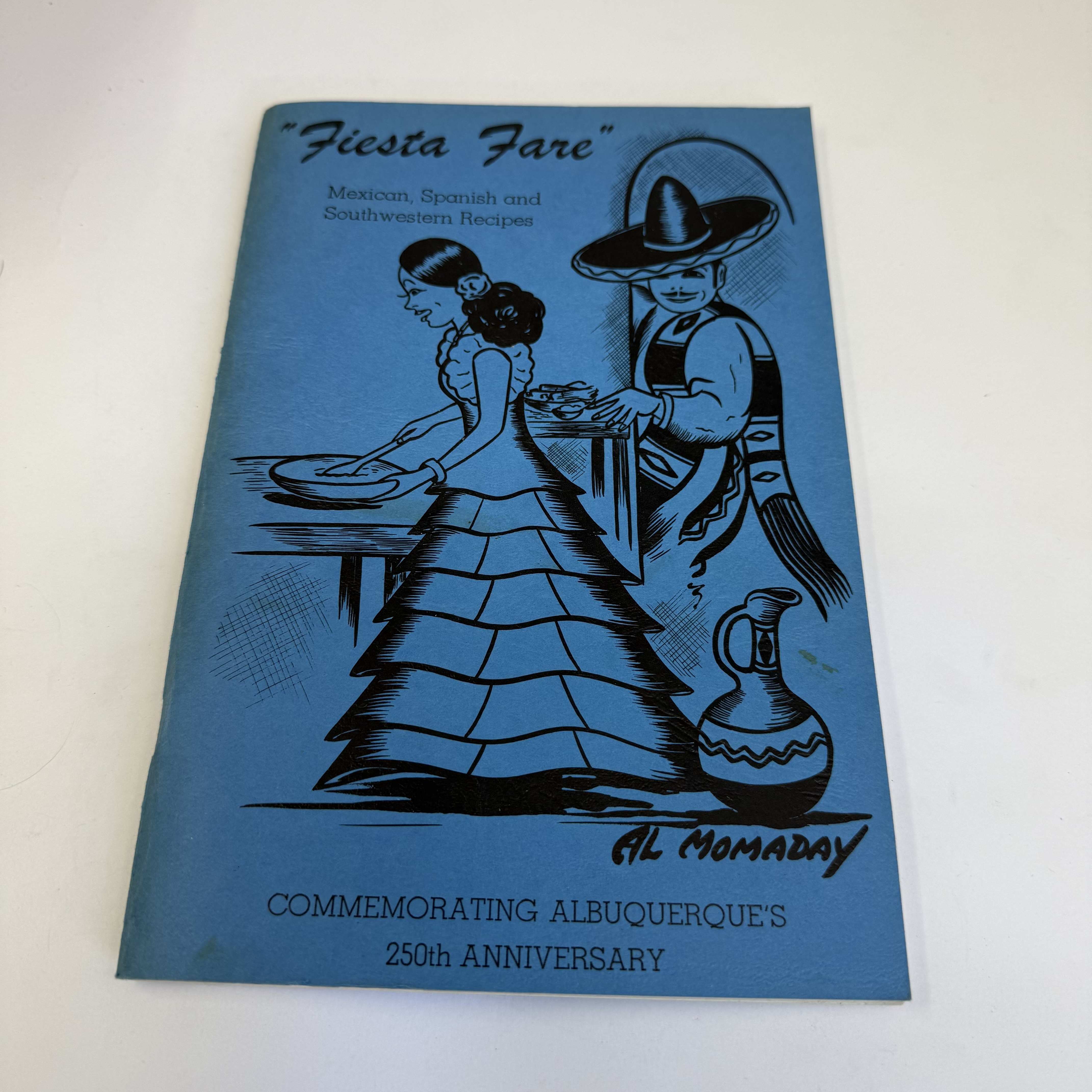 A 1956 commemorative cookbook 'Fiesta Fare: Mexican, Spanish and Southwestern Recipes', with cover illustration signed by Al Momaday, published for Albuquerque's 250th anniversary, donated to NMLP from a pile that the library asked the donor to sort.