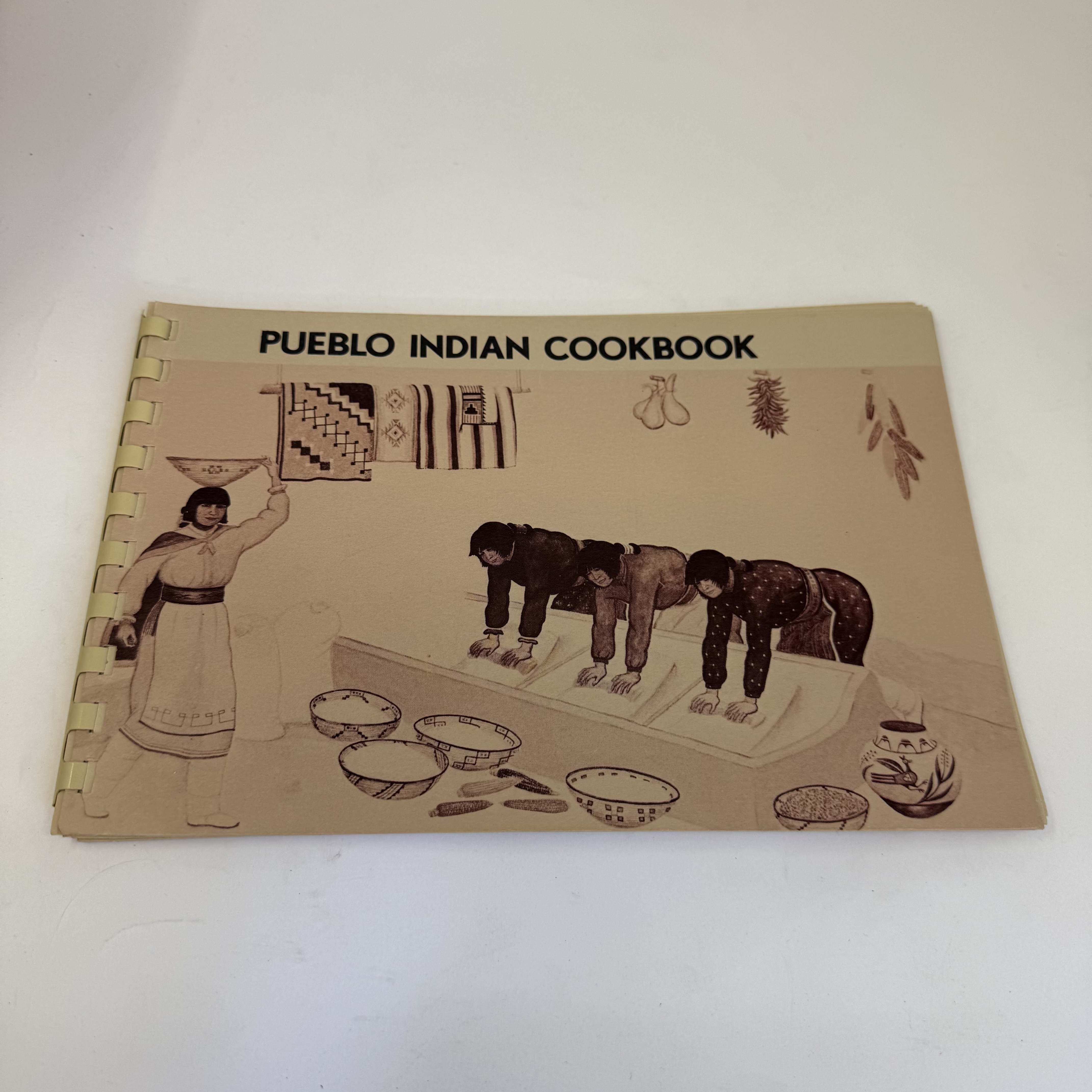 A spiral-bound copy of the Pueblo Indian Cookbook with traditional Pueblo art on the cover, published by the Museum of New Mexico Press, in the donation pile from a donor told to sort first by an Albuquerque library.