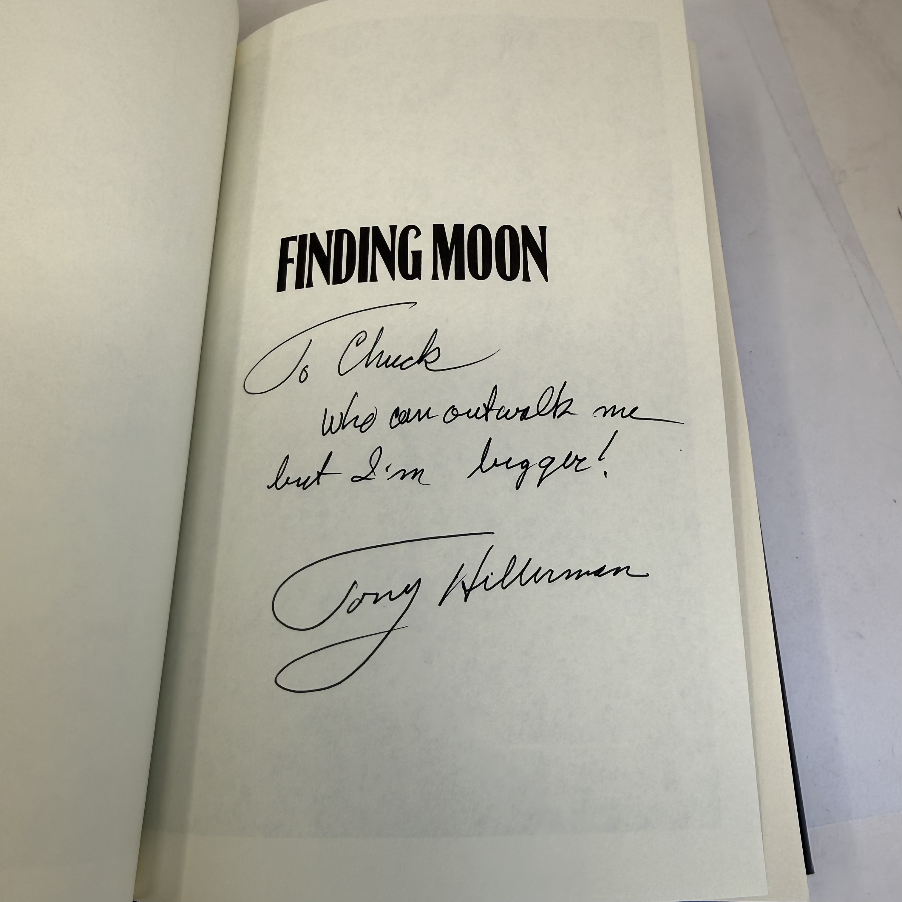 Signed title page of Finding Moon by Tony Hillerman — first edition, personal inscription reading To Chuck who can outwalk me but I am bigger, Tony Hillerman, in bold black ink on the title page