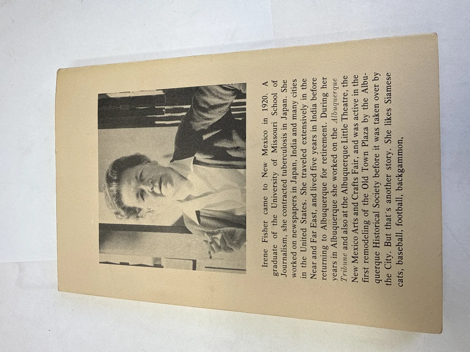 Back cover of Bathtub and Silver Bullet showing author photo of Irene Fisher and biographical text describing her arrival in New Mexico in 1920, journalism career in Japan India and the United States, and work with the Albuquerque Tribune, Albuquerque Little Theatre, New Mexico Arts and Crafts Fair, and Albuquerque Historical Society Old Town Plaza restoration. Photographed at the New Mexico Literacy Project sorting desk in Albuquerque.