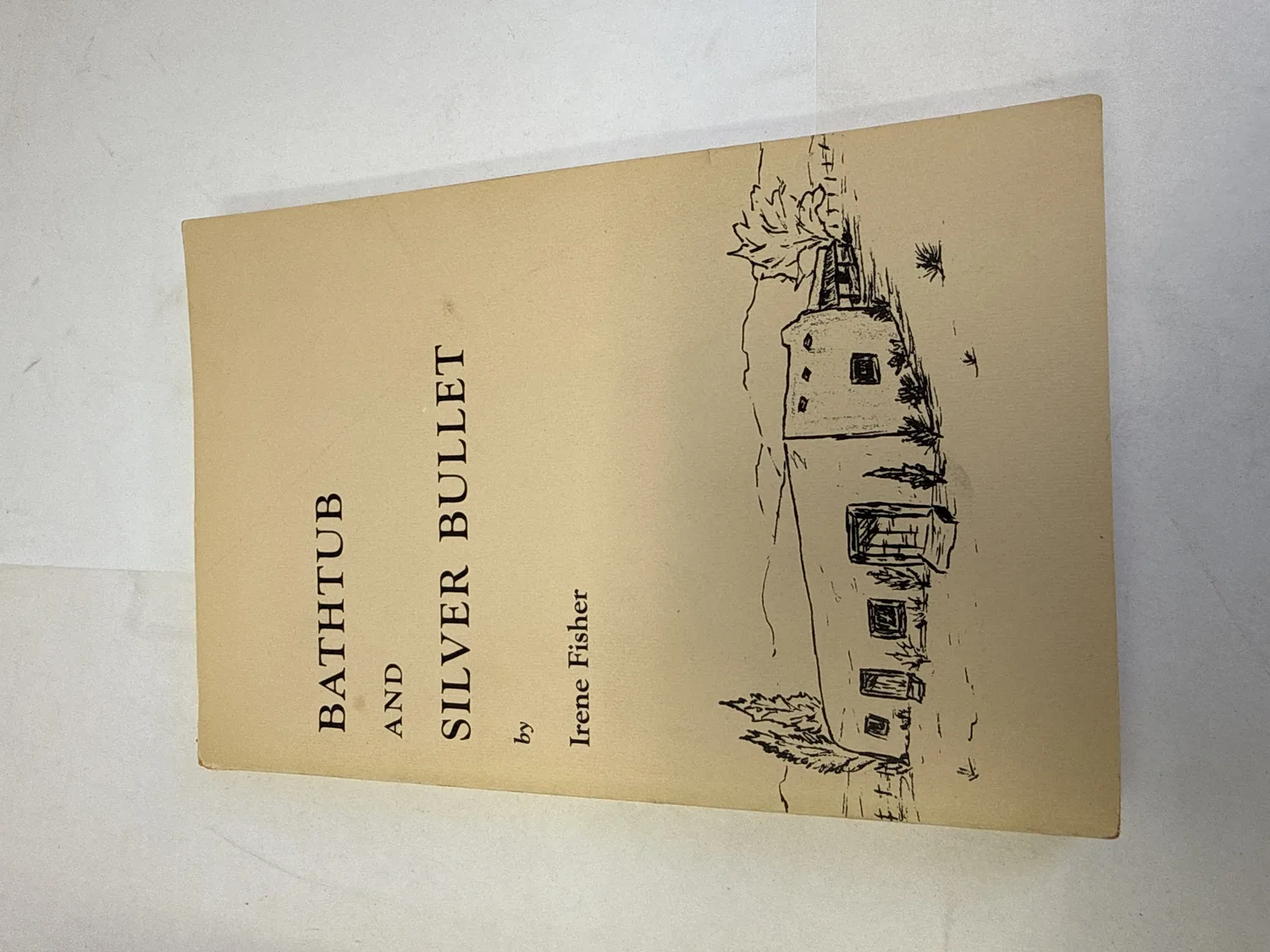 Front cover of Bathtub and Silver Bullet by Irene Fisher showing pen-and-ink illustration of a New Mexico adobe compound by Barbara Lawrence, tan softcover, published by Albuquerque Historical Society through The Tumbleweed Press Placitas New Mexico. Photographed at the New Mexico Literacy Project sorting desk in Albuquerque.