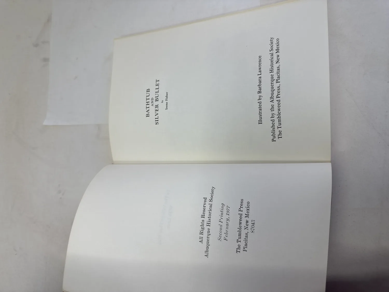 Title page and copyright page spread of Bathtub and Silver Bullet by Irene Fisher, illustrated by Barbara Lawrence, published by the Albuquerque Historical Society, The Tumbleweed Press Placitas New Mexico 87043, Second Printing February 1977, All Rights Reserved Albuquerque Historical Society. Photographed at the New Mexico Literacy Project sorting desk in Albuquerque.