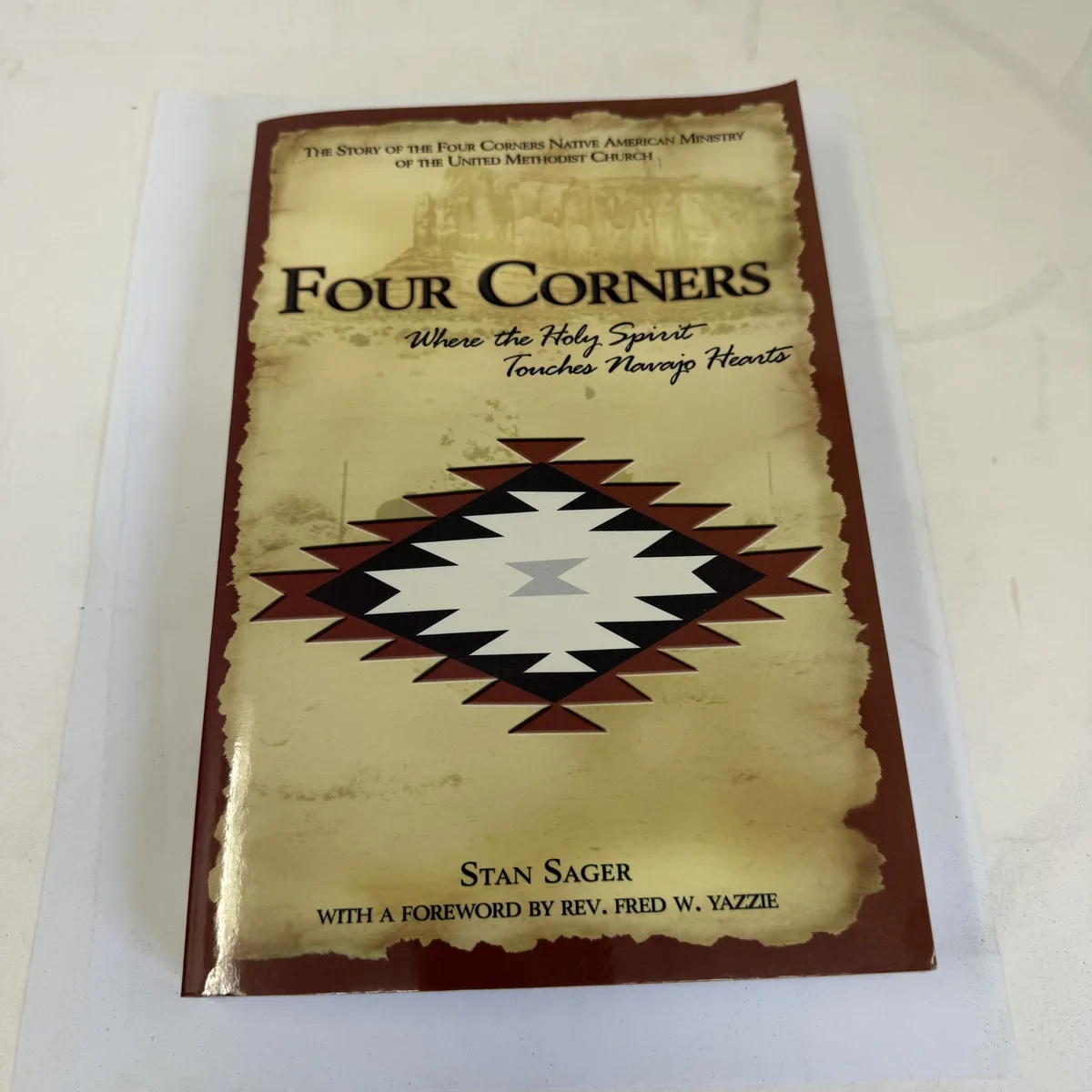 Front cover of Four Corners Where the Holy Spirit Touches Navajo Hearts The Story of the Four Corners Native American Ministry of the United Methodist Church by Stan Sager, Providence House Publishers 2007, featuring Navajo rug design by Alice Mary Yazzie and desert mesa landscape, photographed at the New Mexico Literacy Project sorting desk in Albuquerque