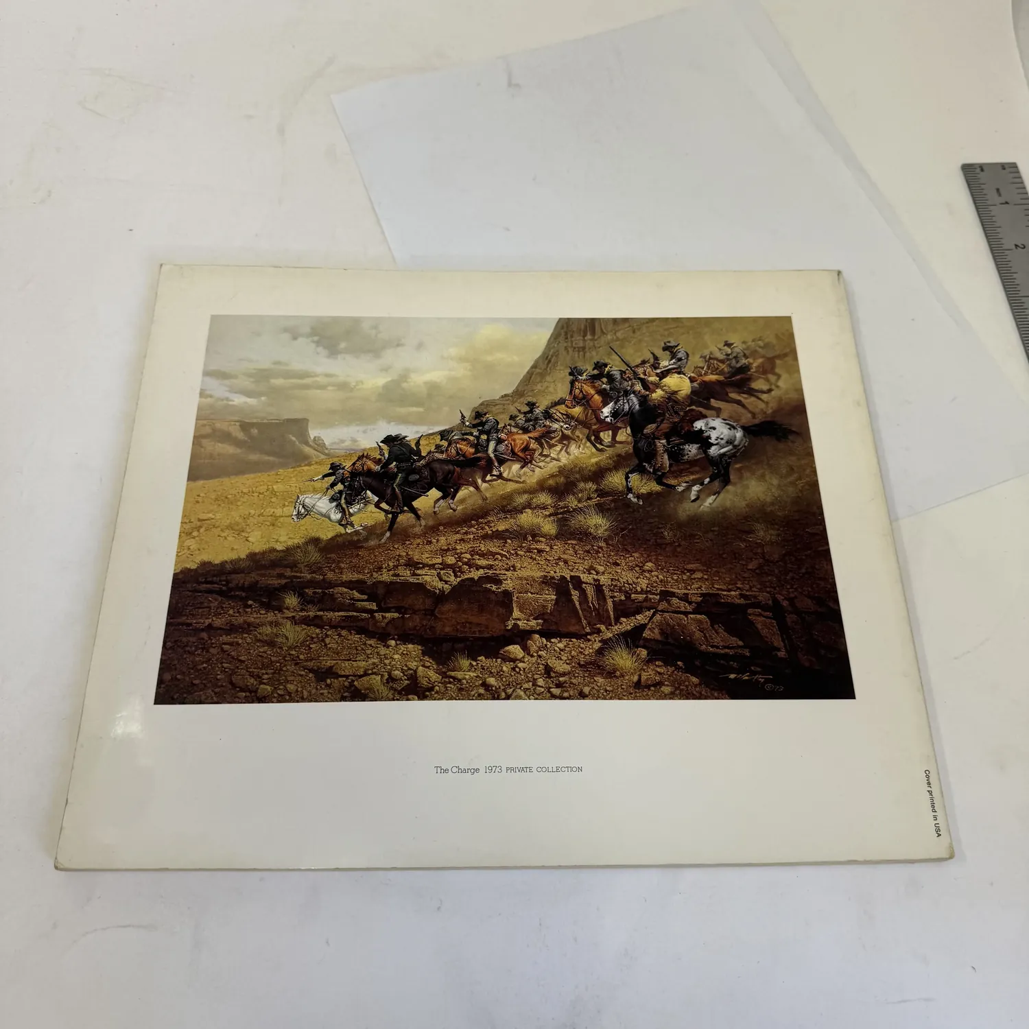 Back cover of The Western Paintings of Frank C. McCarthy showing The Charge (1973), a dramatic frontier cavalry action painting from a Private Collection. Cover printed in USA. Ballantine Books large-format art book. Photographed at the New Mexico Literacy Project sorting desk in Albuquerque.