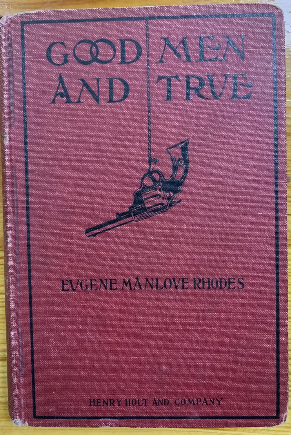 Front cover of the first edition of Good Men and True by Eugene Manlove Rhodes, Henry Holt and Company 1910, red cloth binding with black-stamped revolver illustration and title lettering, the foundational Rhodes first edition