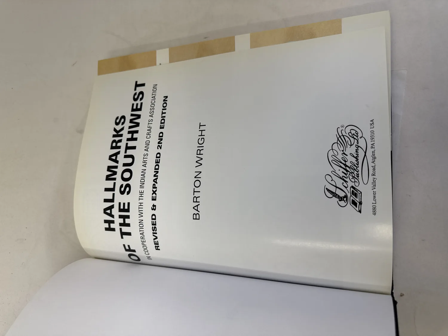 Title page of Hallmarks of the Southwest by Barton Wright, showing full publication details including In Cooperation with the Indian Arts and Crafts Association, Revised and Expanded 2nd Edition, Schiffer Publishing Ltd logo and address at 4880 Lower Valley Road, Atglen PA 19310 USA. Photographed at the New Mexico Literacy Project sorting desk in Albuquerque.