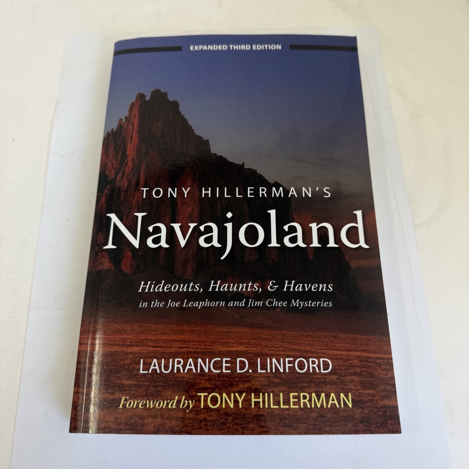 Front cover of Tony Hillerman's Navajoland: Hideouts, Haunts, and Havens in the Joe Leaphorn and Jim Chee Mysteries, Expanded Third Edition by Laurance D. Linford — University of Utah Press, desert mesa at sunset cover photo by Robert McKenzie, blue Expanded Third Edition banner