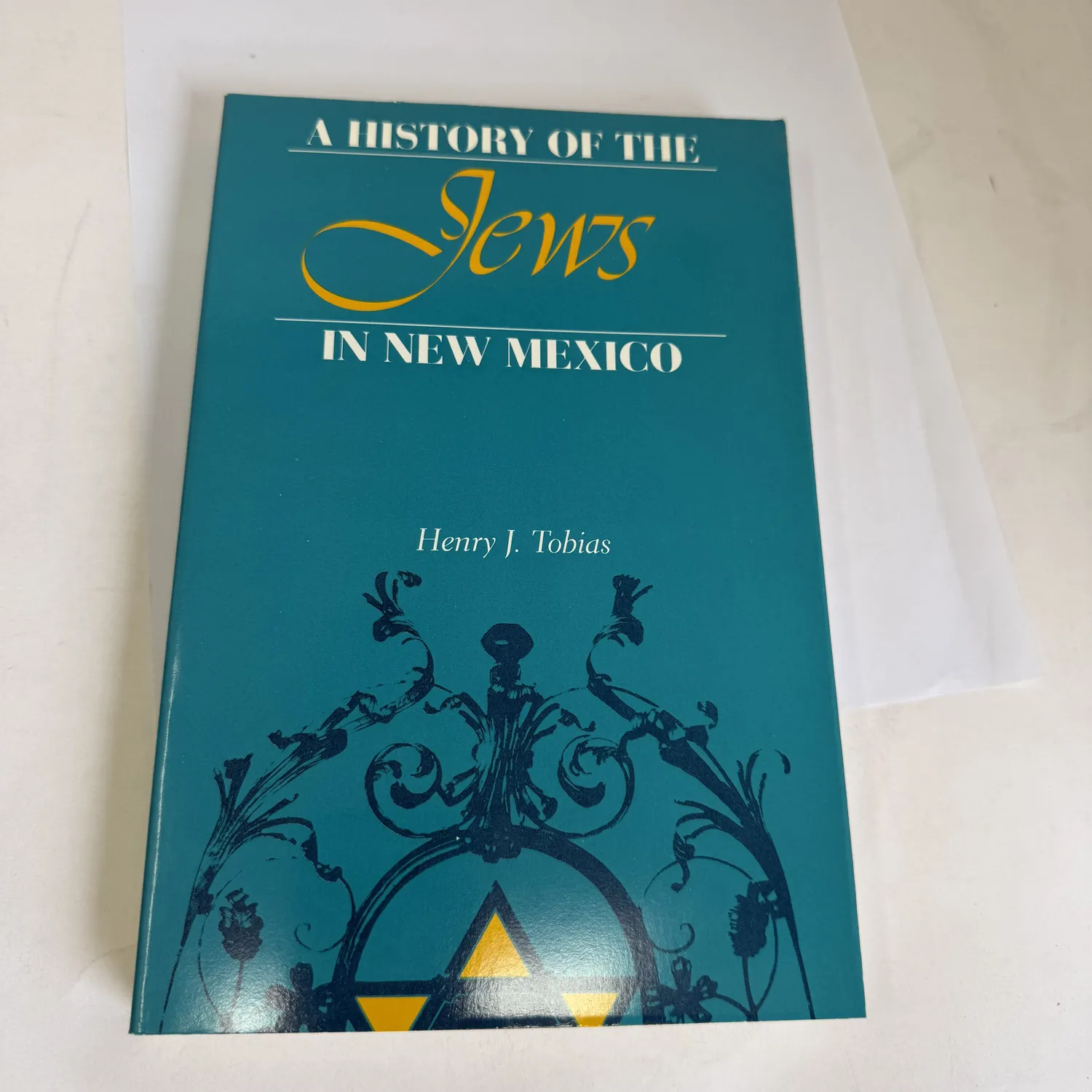 Front cover of A History of the Jews in New Mexico by Henry J. Tobias — teal cover with ornate wrought-iron gate design and gold Star of David, University of New Mexico Press