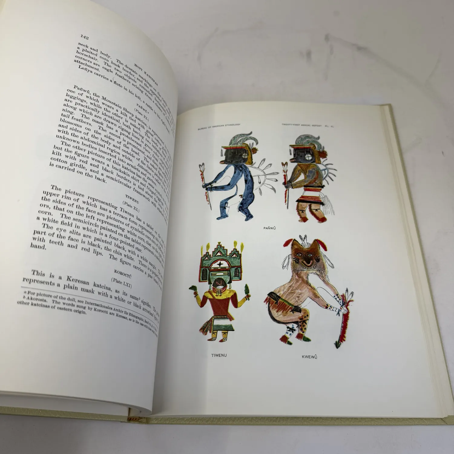 Color plate from Hopi Katcinas by Fewkes showing four kachina figures drawn by Native Hopi artists — Pañwū the Mountain Sheep katcina in blue with zigzag lightning symbols, a second Pañwū variant, Tiwenu with terraced tableta mask and green face, and Kwewū the Wolf kachina in natural brown with spotted body. Page 142, Bureau of American Ethnology Twenty-First Annual Report, public domain 1903