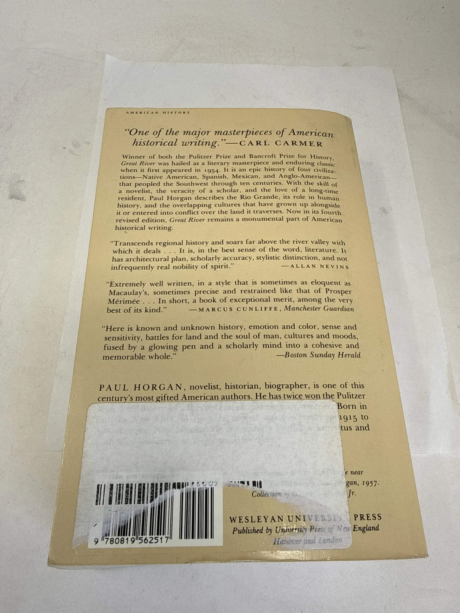 Back cover of Great River by Paul Horgan showing critical blurbs from Carl Carmer, Allan Nevins, Marcus Cunliffe in the Manchester Guardian, and the Boston Sunday Herald, with Horgan biographical note, Wesleyan University Press and University Press of New England imprint, and ISBN barcode. Photographed at the New Mexico Literacy Project sorting desk in Albuquerque.