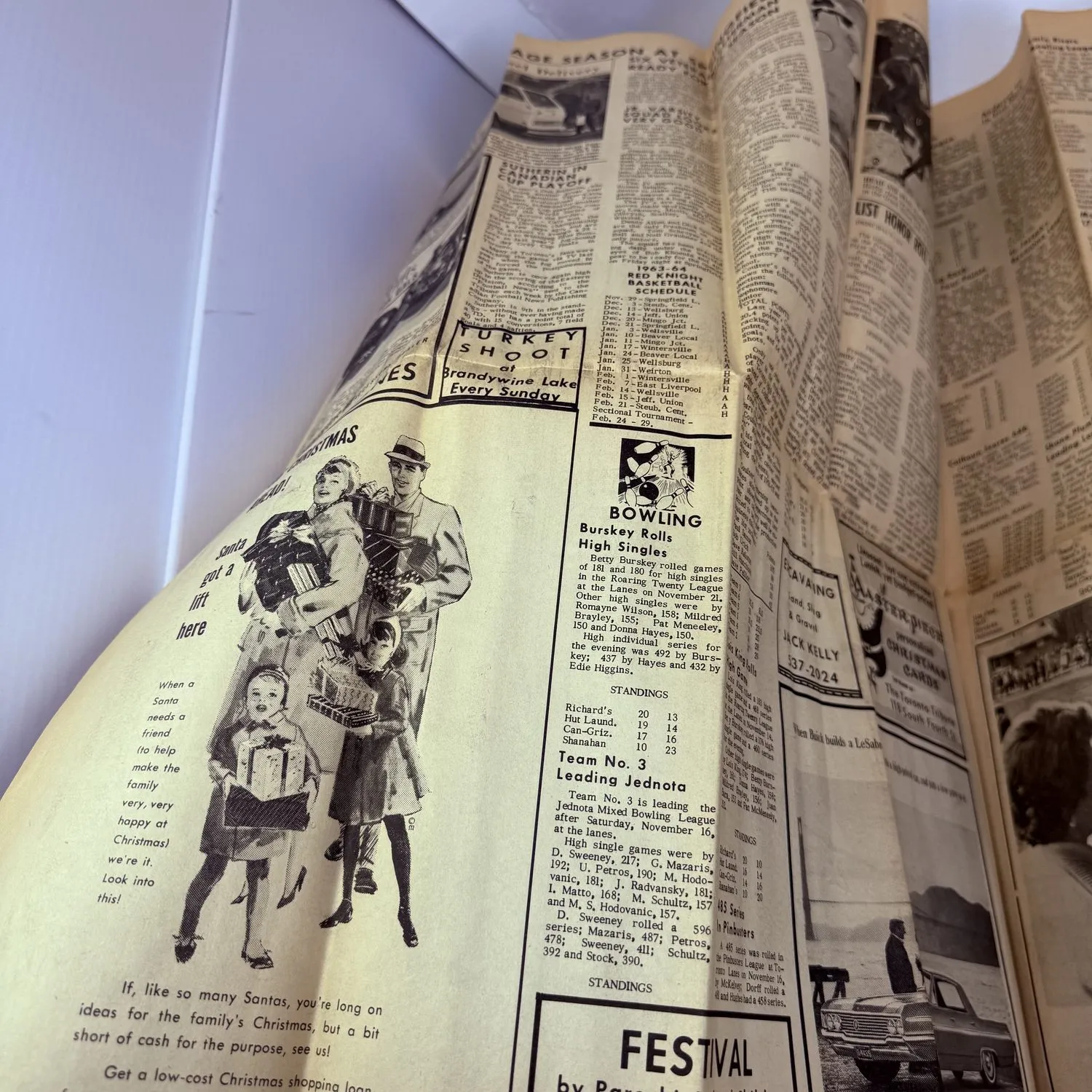 Sports and entertainment pages of the Toronto Tribune November 27 1963, showing bowling league scores and standings, Turkey Shoot at Brandywine Lake Every Sunday advertisement, high school basketball schedule, and Christmas shopping advertisements with illustrations of families carrying presents. Small-town community life the week of the Kennedy assassination.
