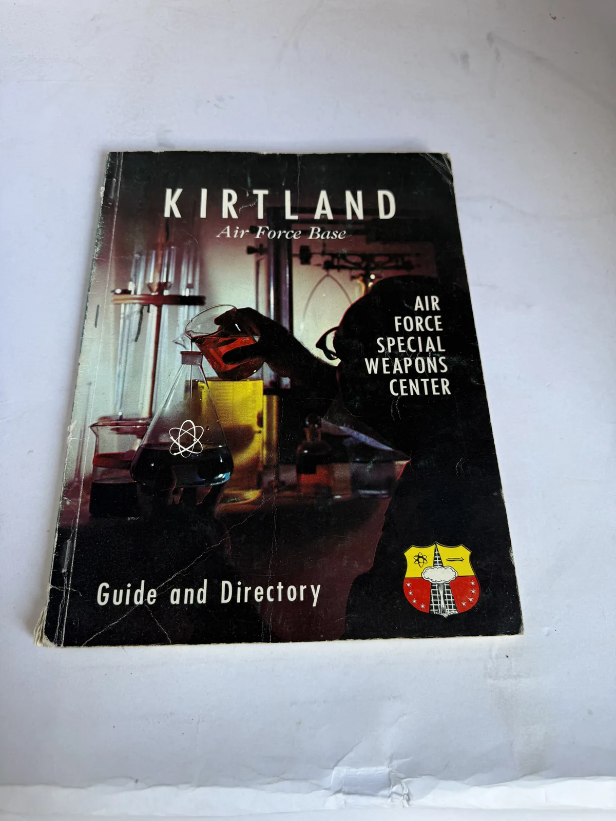 Cover of the Kirtland Air Force Base Guide and Directory for the Air Force Special Weapons Center, illustrated with aircraft and missile artwork, photographed at New Mexico Literacy Project