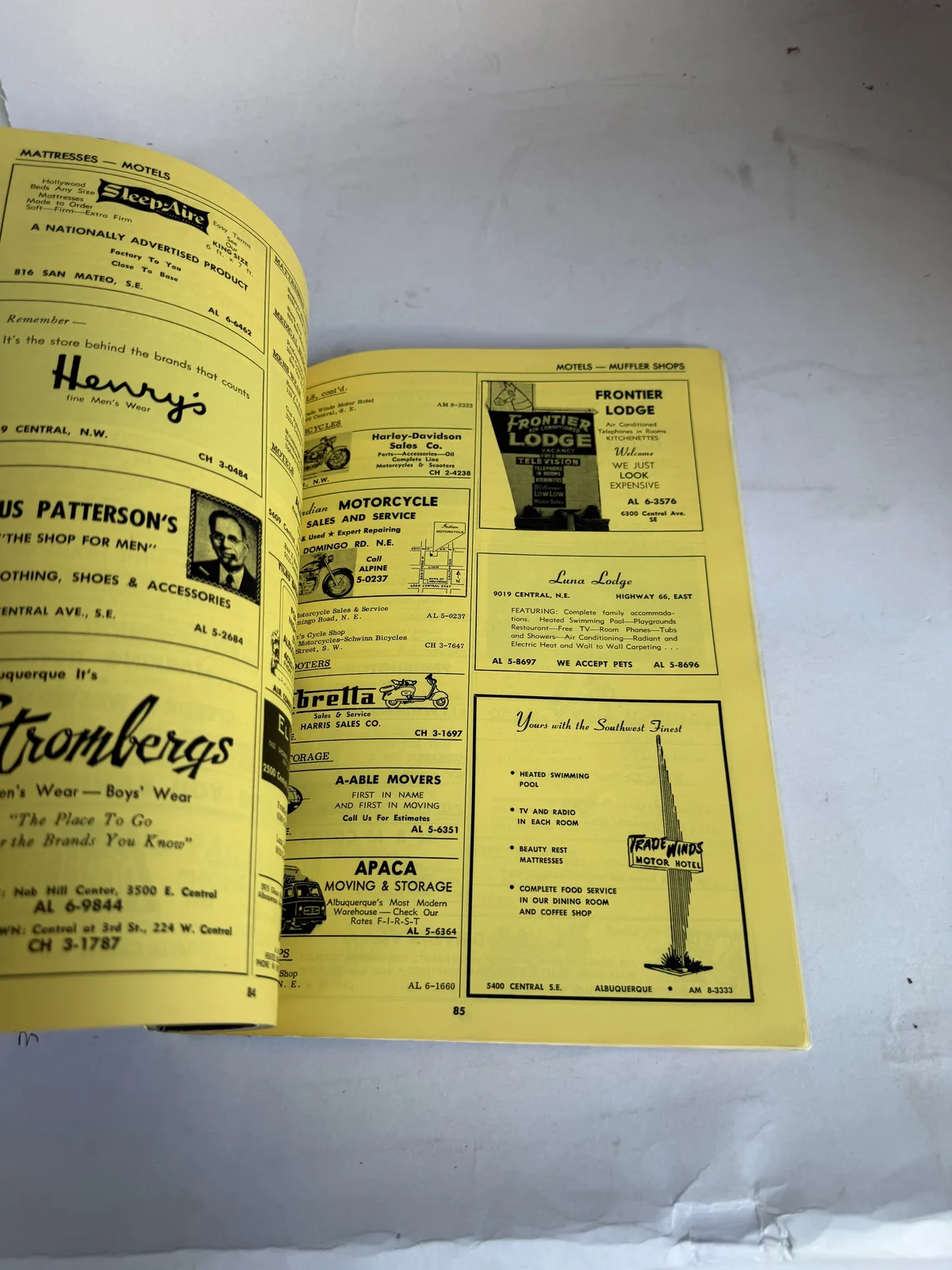 Interior advertising pages of the Kirtland base guide showing mid-century Albuquerque businesses including Fedway, Nature's Motor Co and local merchants, photographed at New Mexico Literacy Project