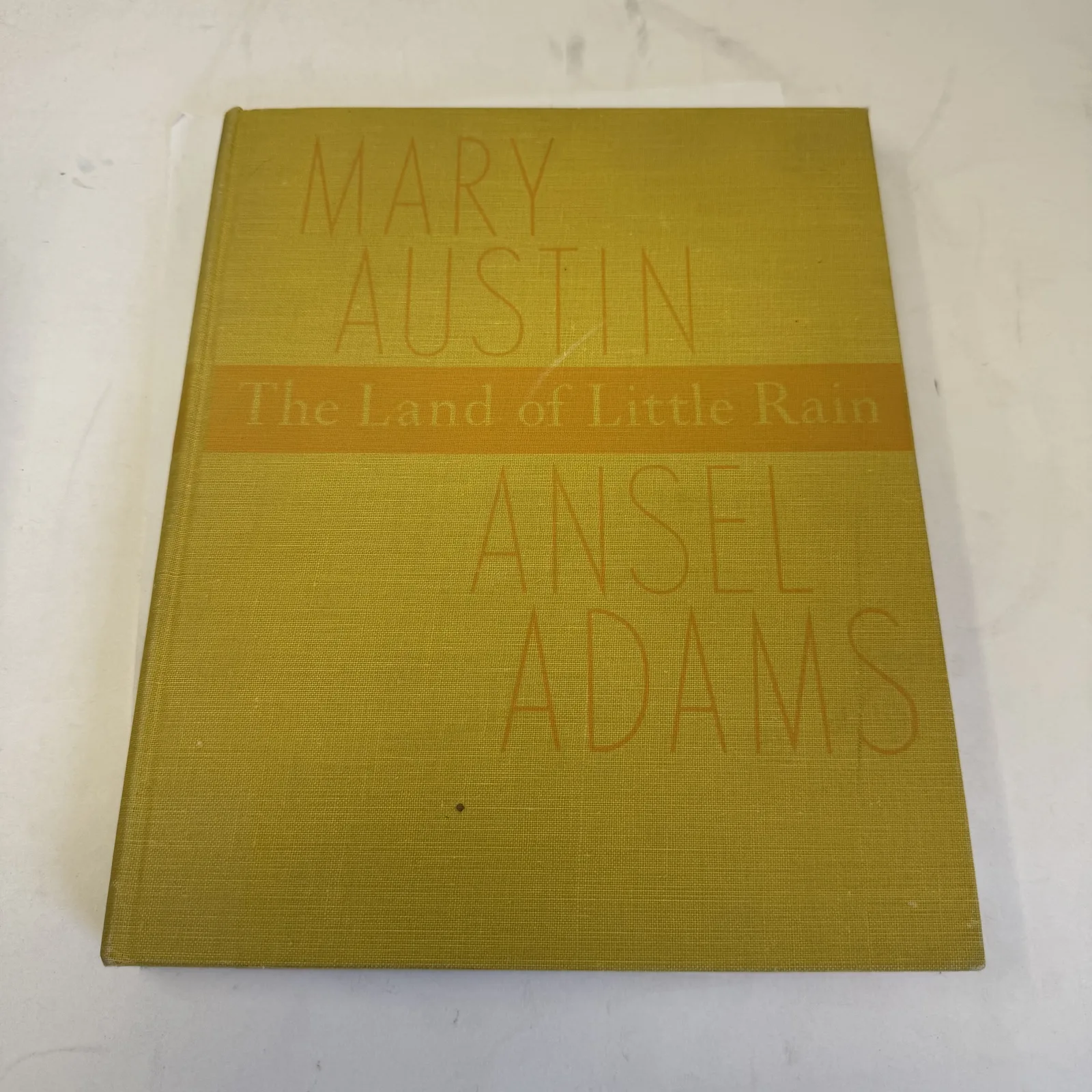 Yellow cloth cover of The Land of Little Rain 1950 Houghton Mifflin photographic edition with printed band naming Mary Austin and Ansel Adams, photographed at New Mexico Literacy Project