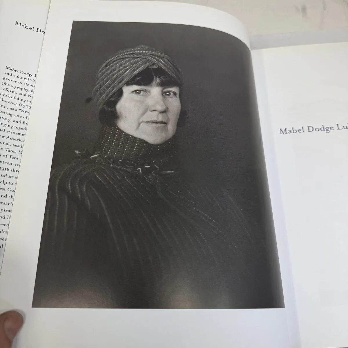 Black and white portrait photograph of Mabel Dodge Luhan wearing a striped turban headwrap and striped garment, reproduced in Mabel Dodge Luhan and Company — photographed by Josh Eldred at NMLP workspace