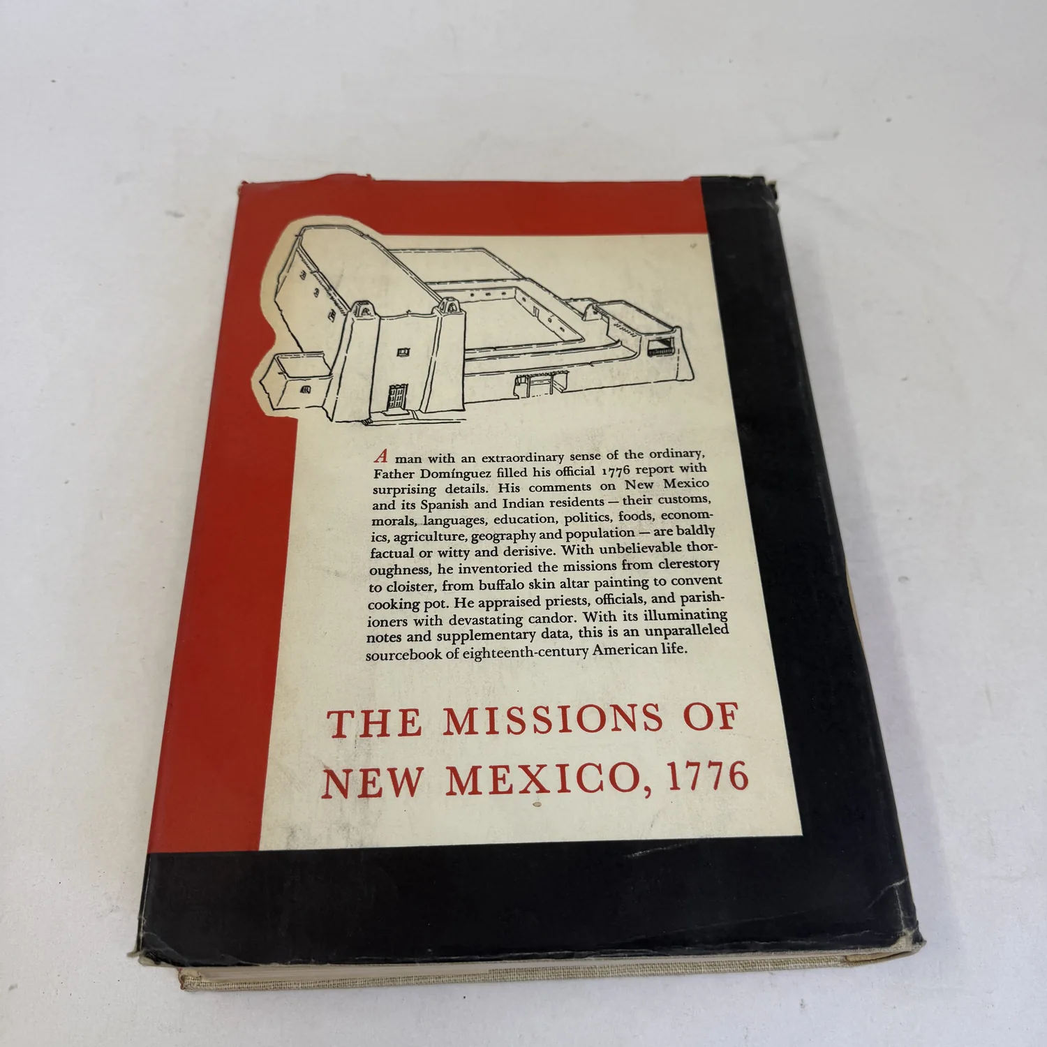 Rear panel of the Missions of New Mexico, 1776 dust jacket with a drawing of a mission complex above the publisher's description, photographed at New Mexico Literacy Project