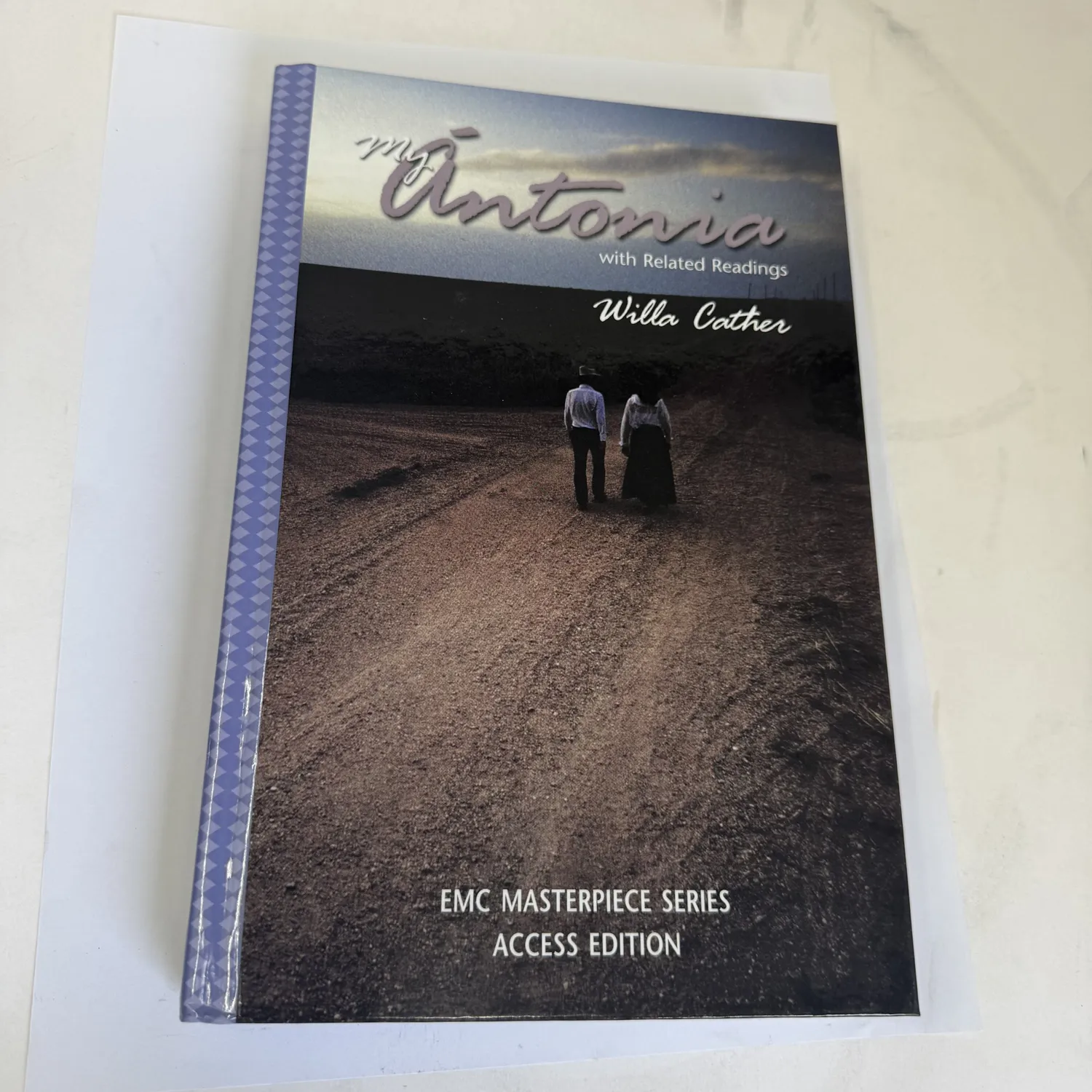 Front cover of My Ántonia by Willa Cather, EMC Masterpiece Series Access Edition copyright 2003 by EMC Corporation, pastoral illustration of a young woman in prairie landscape, study edition from an Albuquerque estate donation, photographed at the New Mexico Literacy Project sorting desk