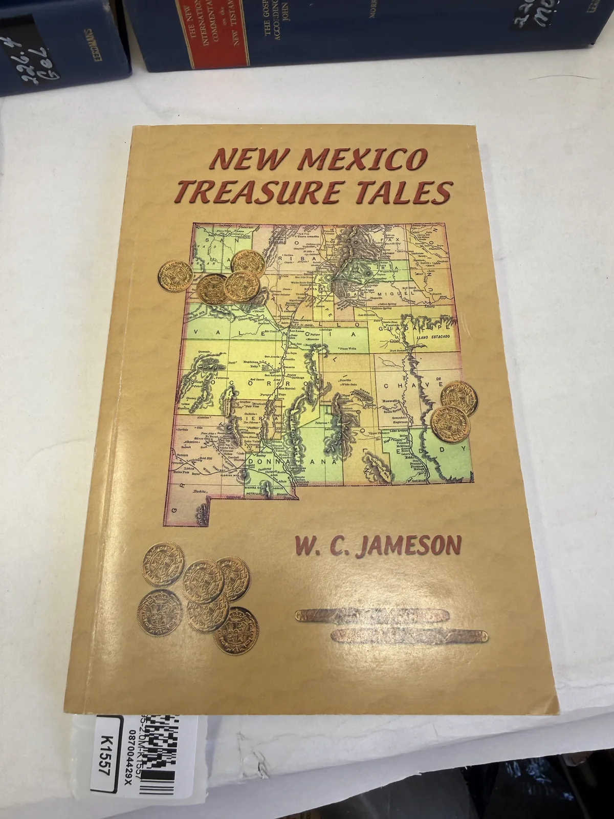 Cover of New Mexico Treasure Tales by W C Jameson with a map of New Mexico and gold coins, photographed at New Mexico Literacy Project