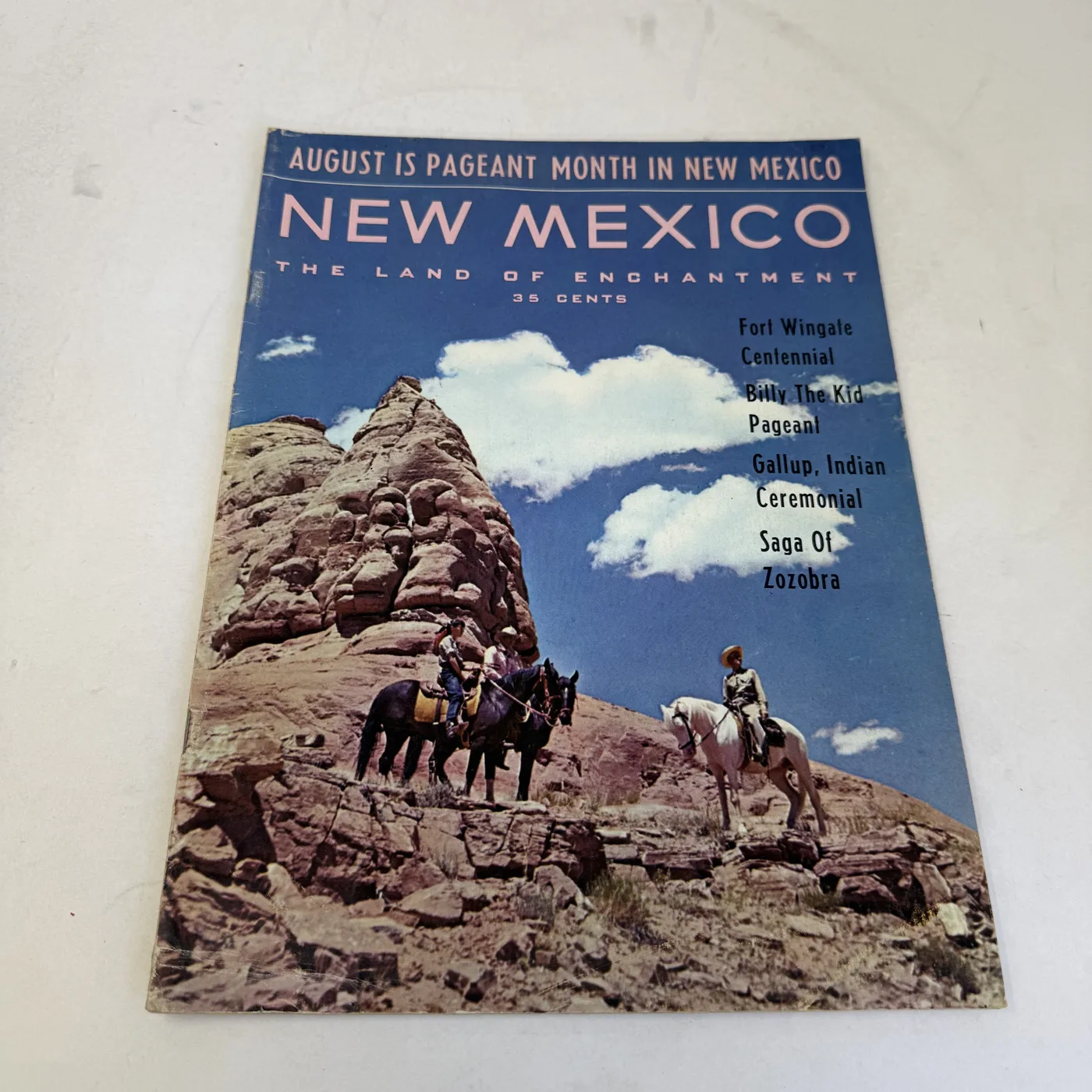 New Mexico Magazine August 1962 cover: riders on horseback below a sandstone formation, cover lines for Fort Wingate Centennial, Billy the Kid Pageant, Gallup Indian Ceremonial, and Saga of Zozobra — photographed at New Mexico Literacy Project