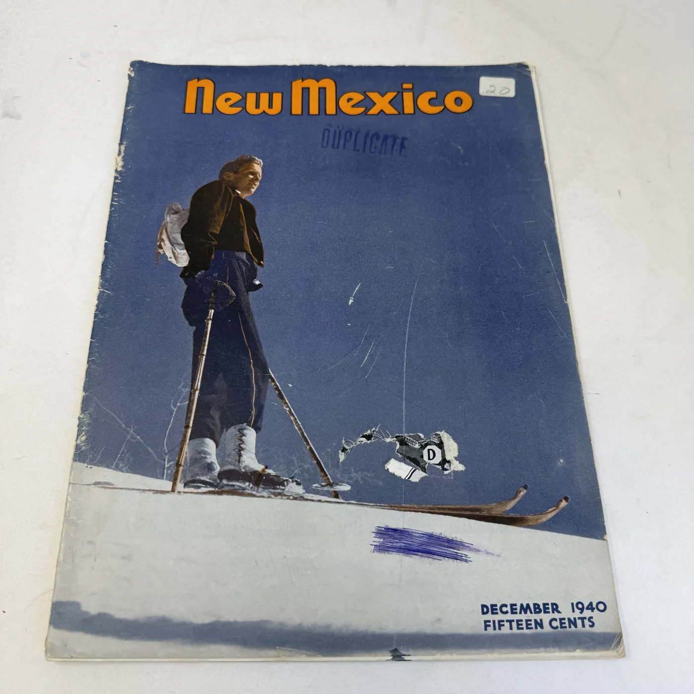 New Mexico Magazine December 1940 cover: skier on a snow slope, stamped DUPLICATE, fifteen cents — photographed at New Mexico Literacy Project