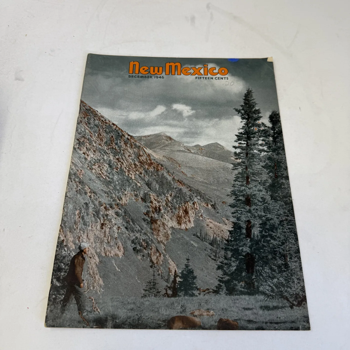 New Mexico Magazine December 1946 cover: walker below timberline in a high mountain valley, old pencil price mark in the sky — photographed at New Mexico Literacy Project