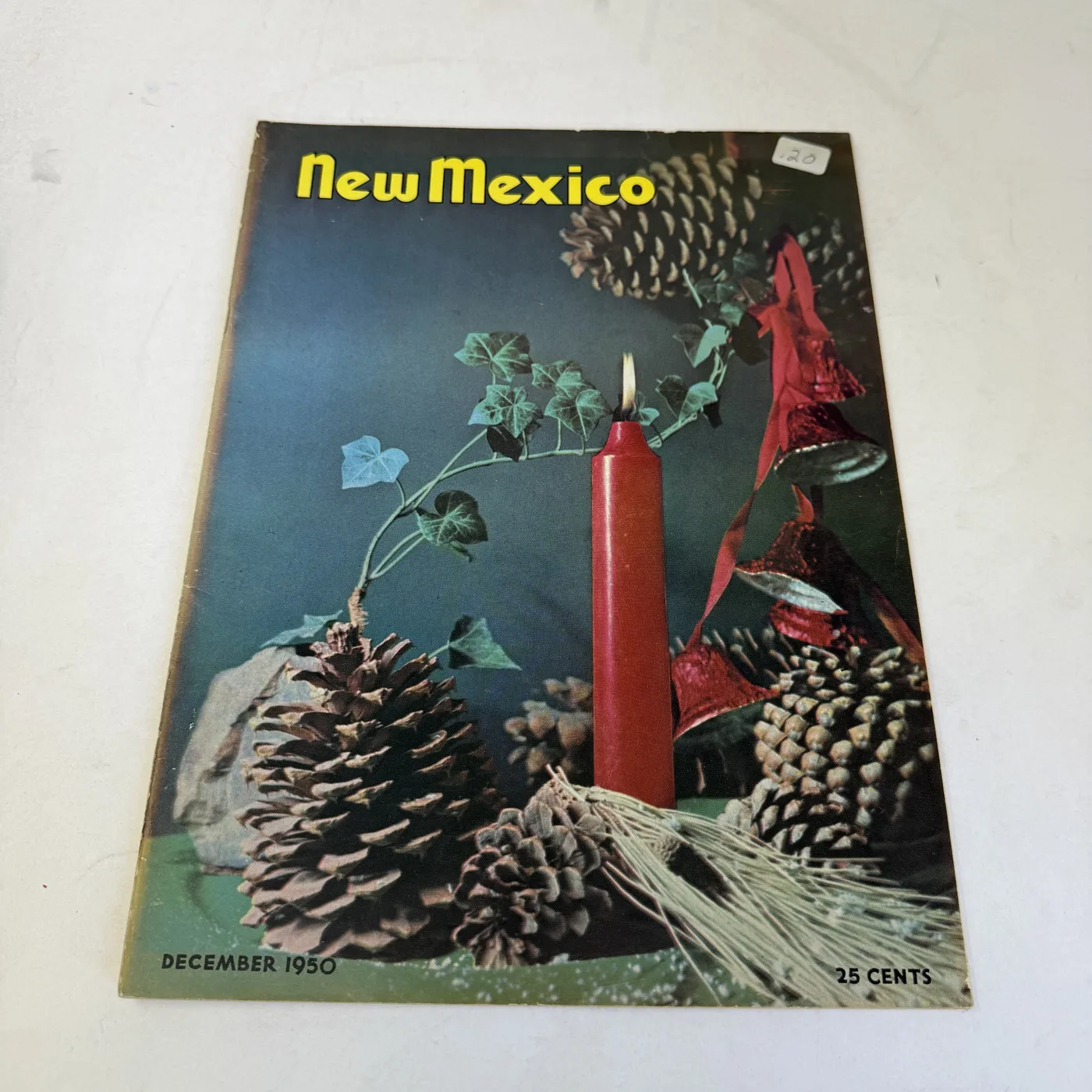 New Mexico Magazine December 1950 cover: Christmas still life of pinon cones, red candle, and greenery — photographed at New Mexico Literacy Project