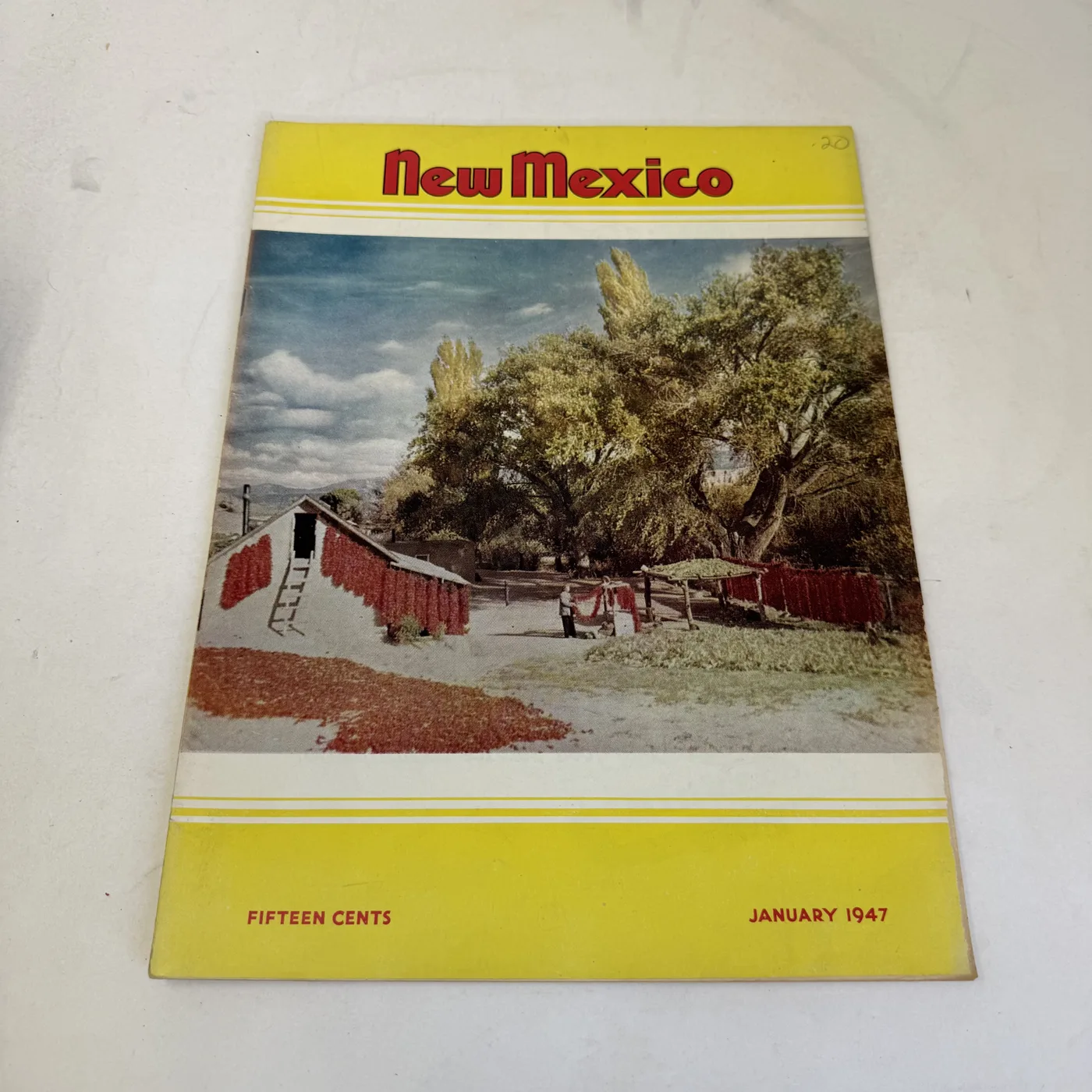 New Mexico Magazine January 1947 cover: red chile ristras drying on a rack in a farmyard, yellow border — photographed at New Mexico Literacy Project