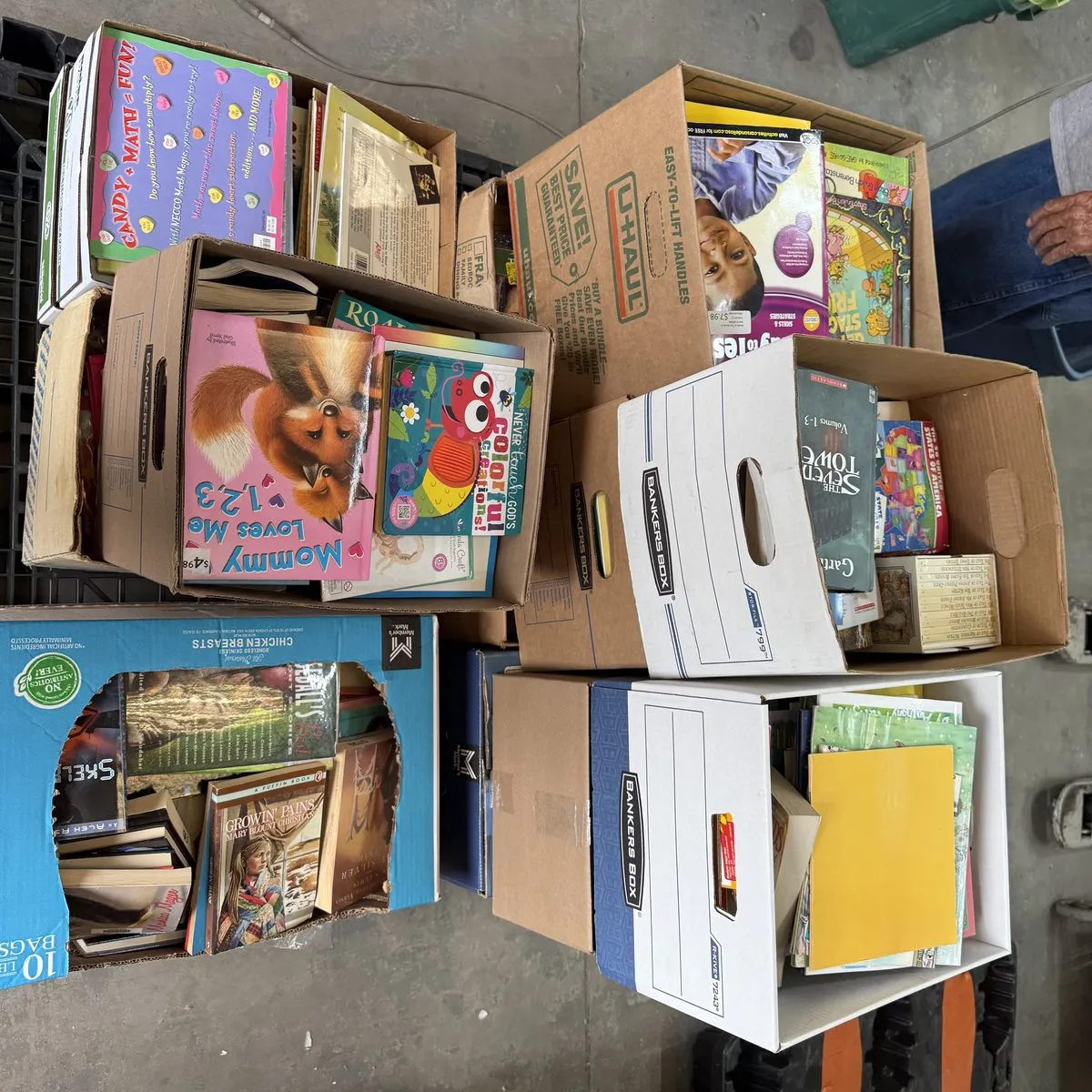 Full pallet of children's books in boxes stacked two to three high, being prepared for distribution to rural New Mexico communities through a volunteer at La Vida Llena retirement community in Albuquerque