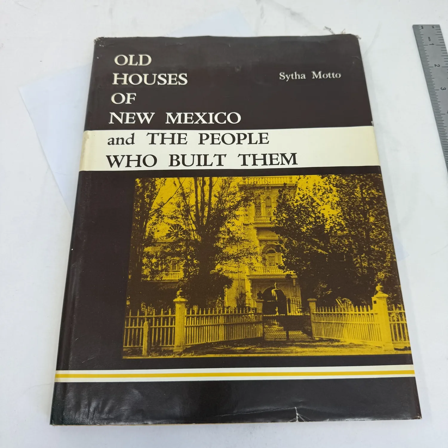 Front cover with dust jacket of Old Houses of New Mexico and the People Who Built Them by Sytha Motto — dark brown and gold dust jacket showing Victorian-style New Mexico house behind wrought iron fence, Calvin Horn Publisher Inc Albuquerque