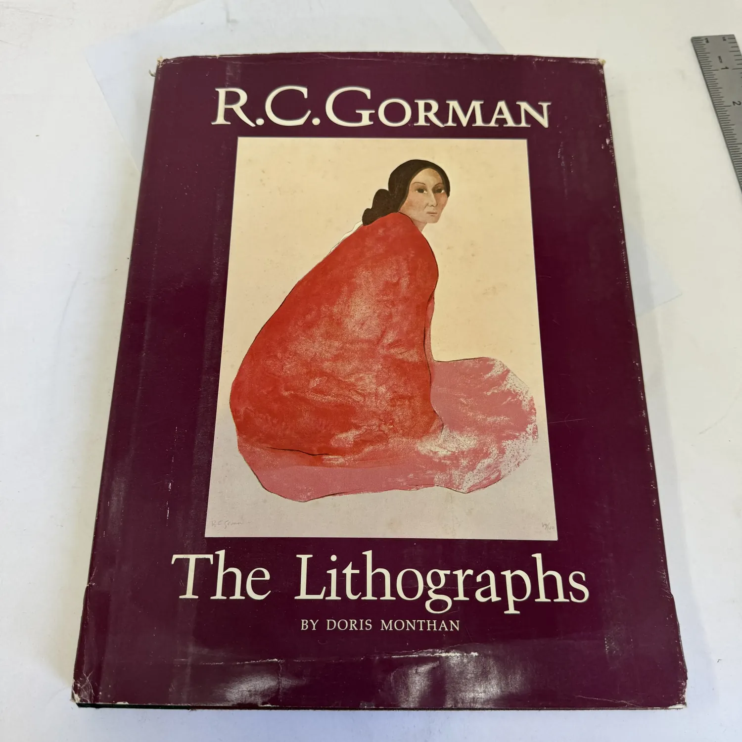 Front cover with dust jacket of R.C. Gorman: The Lithographs by Doris Monthan, Northland Press 1978 — deep plum dust jacket featuring Gorman's seated Navajo woman lithograph in red shawl