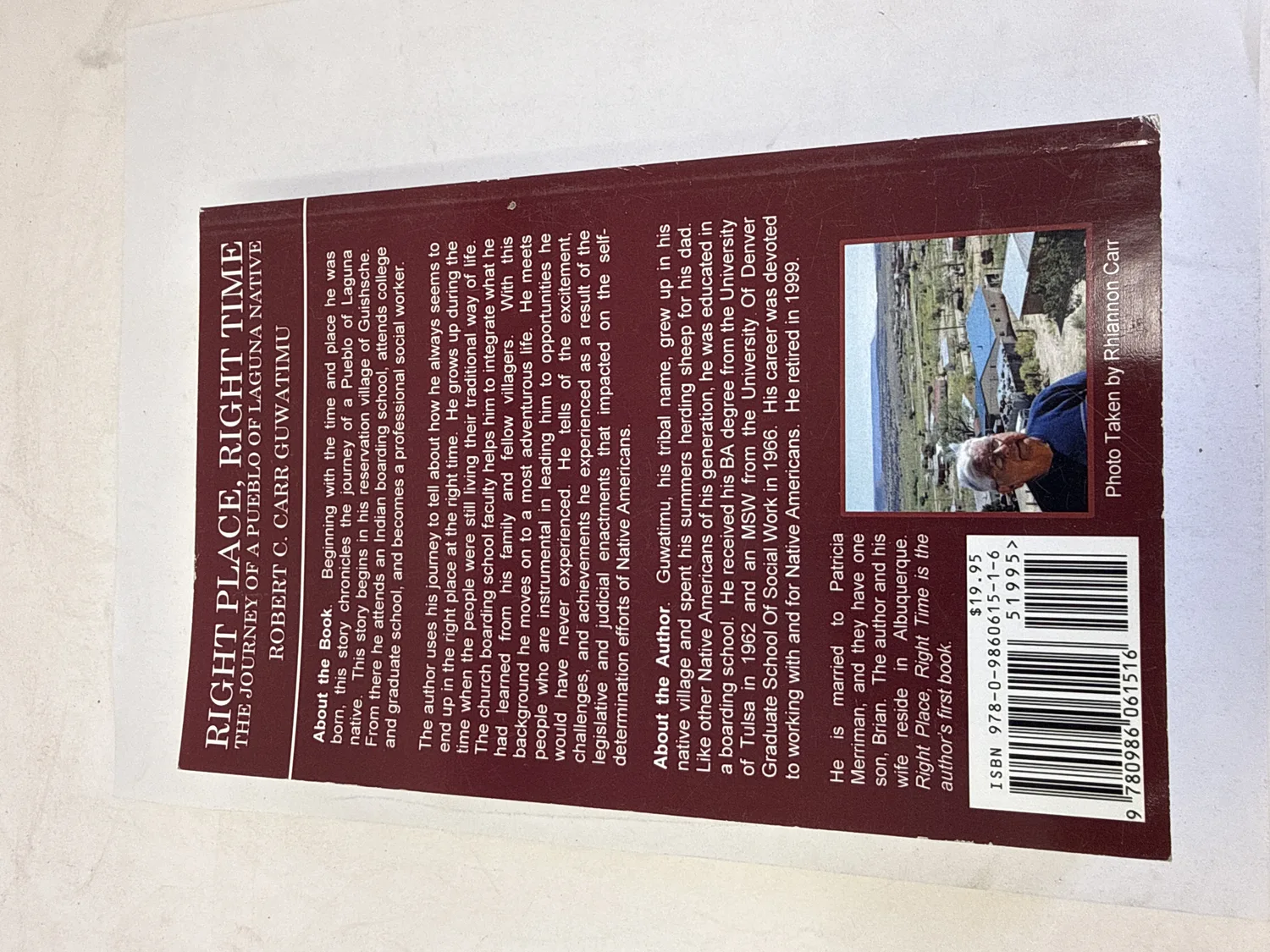 Back cover of Right Place, Right Time by Robert C. Carr (Guwatimu) &mdash; maroon background with About the Book and About the Author sections, author photo by Rhiannon Carr, BA University of Tulsa 1962, MSW University of Denver 1966, ISBN barcode, $19.95. Photographed at the New Mexico Literacy Project sorting desk in Albuquerque.