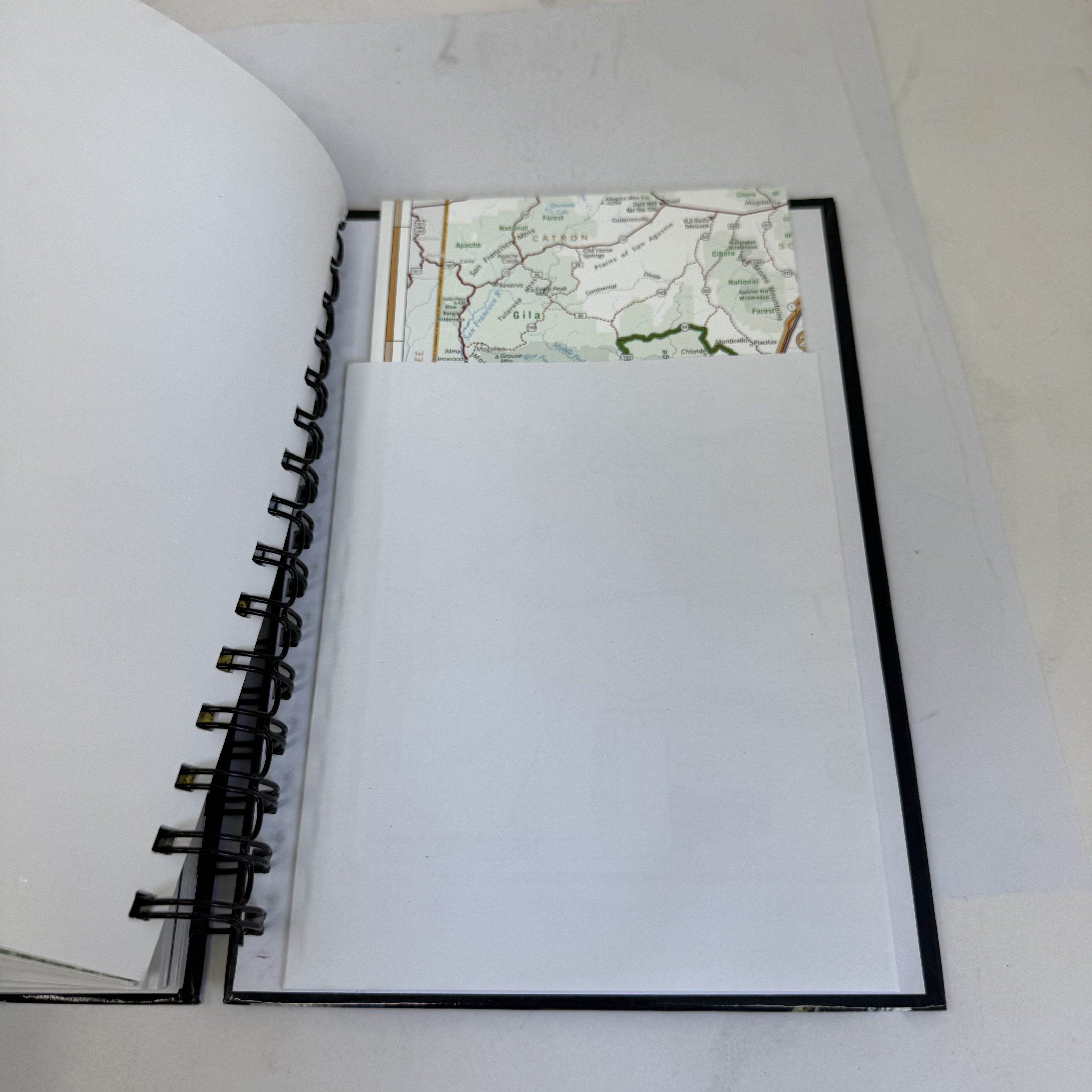 Back pocket of By the Way 25 scenic byways guide showing original fold-out New Mexico state map partially unfolded to reveal Catron County and Gila National Forest area — completeness indicator for this spiral-bound travel guide.