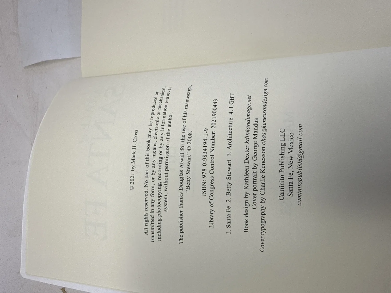 Copyright page of A Tale of Santa Fe showing 2021 date, ISBN 978-0-9834194-1-9, Library of Congress Control Number 2021900443, subject headings Santa Fe Betty Stewart Architecture LGBT, book design by Kathleen Dexter, cover portrait by George Mandus, cover typography by Charlie Kenesson, Caminito Publishing LLC Santa Fe New Mexico. Photographed at the New Mexico Literacy Project sorting desk in Albuquerque.