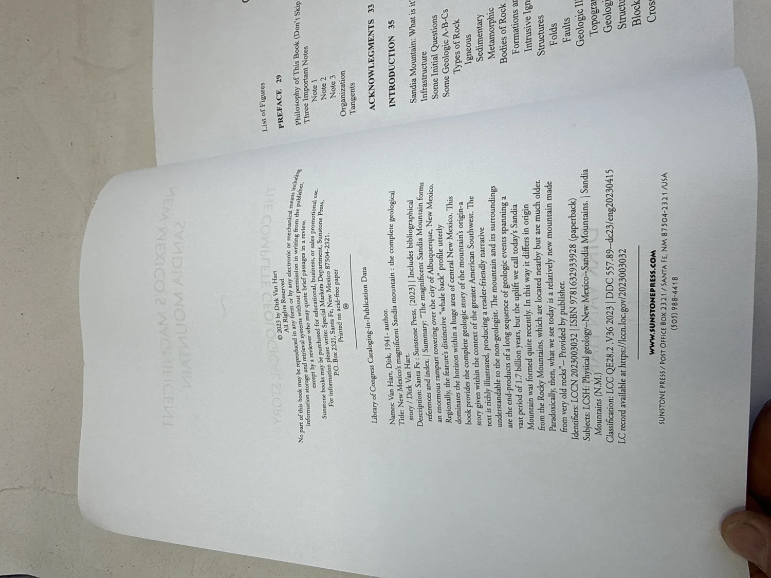 Copyright page and table of contents spread of New Mexico's Magnificent Sandia Mountain by Dirk Van Hart &mdash; Library of Congress data, ISBN 978-1-63293-392-8, LCCN 2023003032, Sunstone Press Santa Fe NM, printed on acid-free paper, chapter listing from Preface through geological formations. Photographed at the New Mexico Literacy Project sorting desk in Albuquerque.