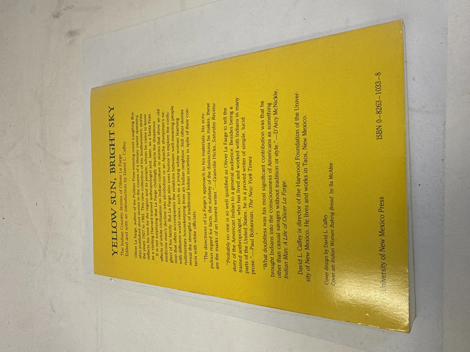 Back cover of Yellow Sun, Bright Sky by Oliver La Farge showing description of the Indian Country stories spanning Navajo and Hopi peoples, with endorsement quote from N. Scott Momaday, ISBN 0-8263-1033-8, University of New Mexico Press. Photographed at the New Mexico Literacy Project sorting desk in Albuquerque.