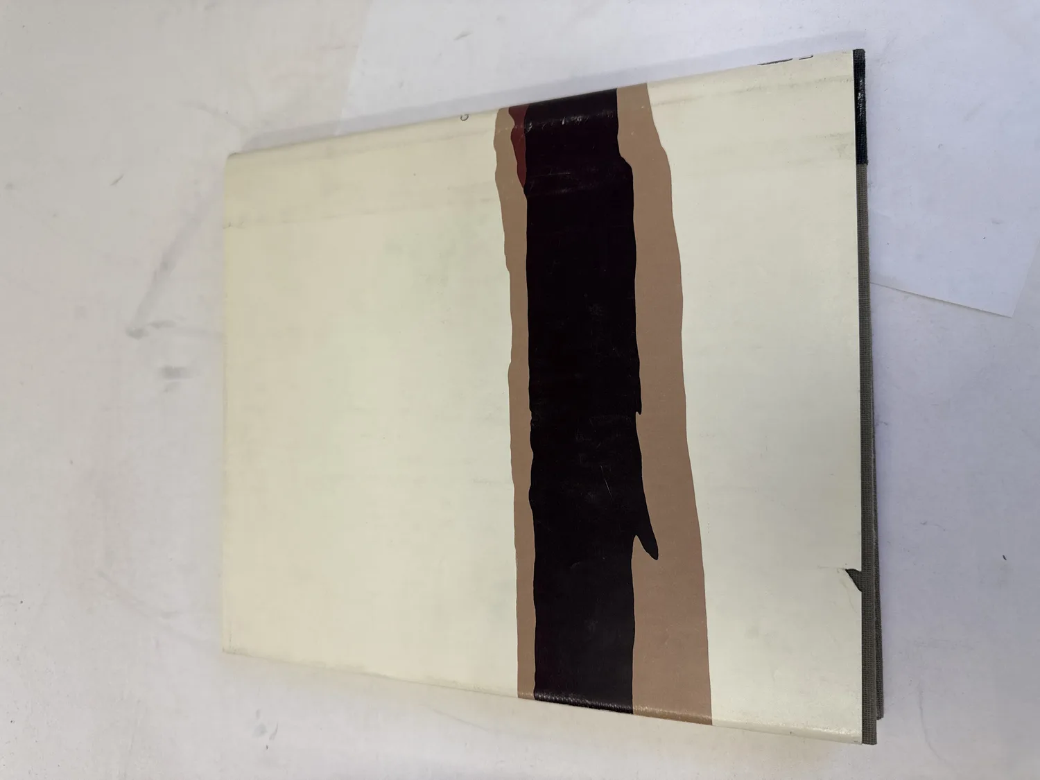 Back cover of The Zunis of Cibola dust jacket showing continuation of the abstract landscape design in black, tan, and cream. Photographed at the New Mexico Literacy Project sorting desk in Albuquerque.